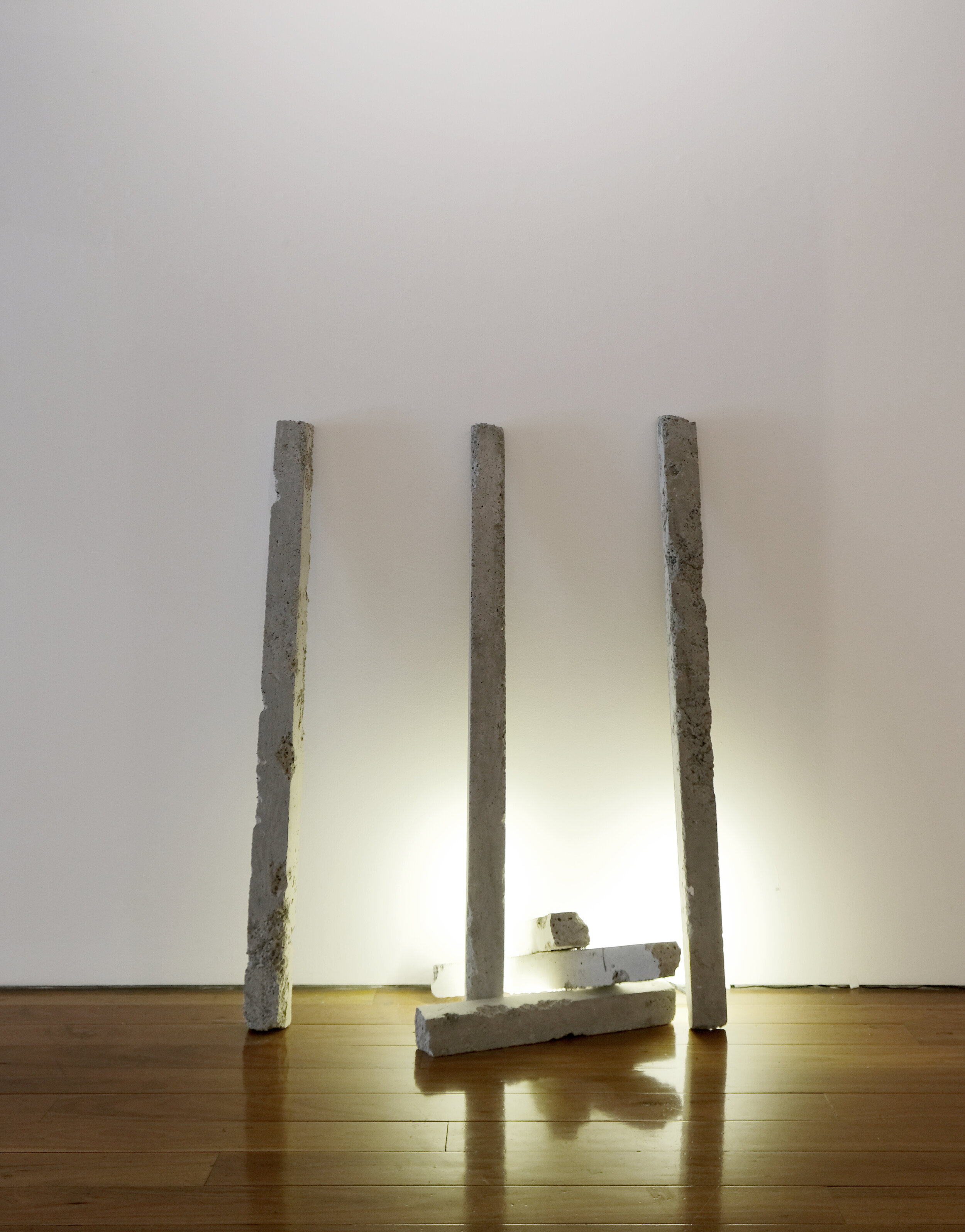 Concrete slabs leaning against a white wall on a wooden floor