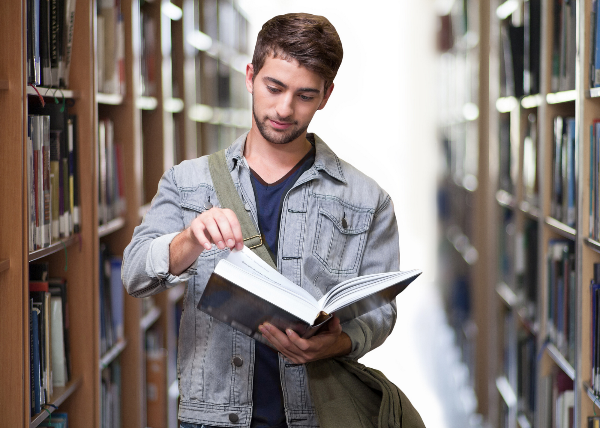 Young man reading a book in a library