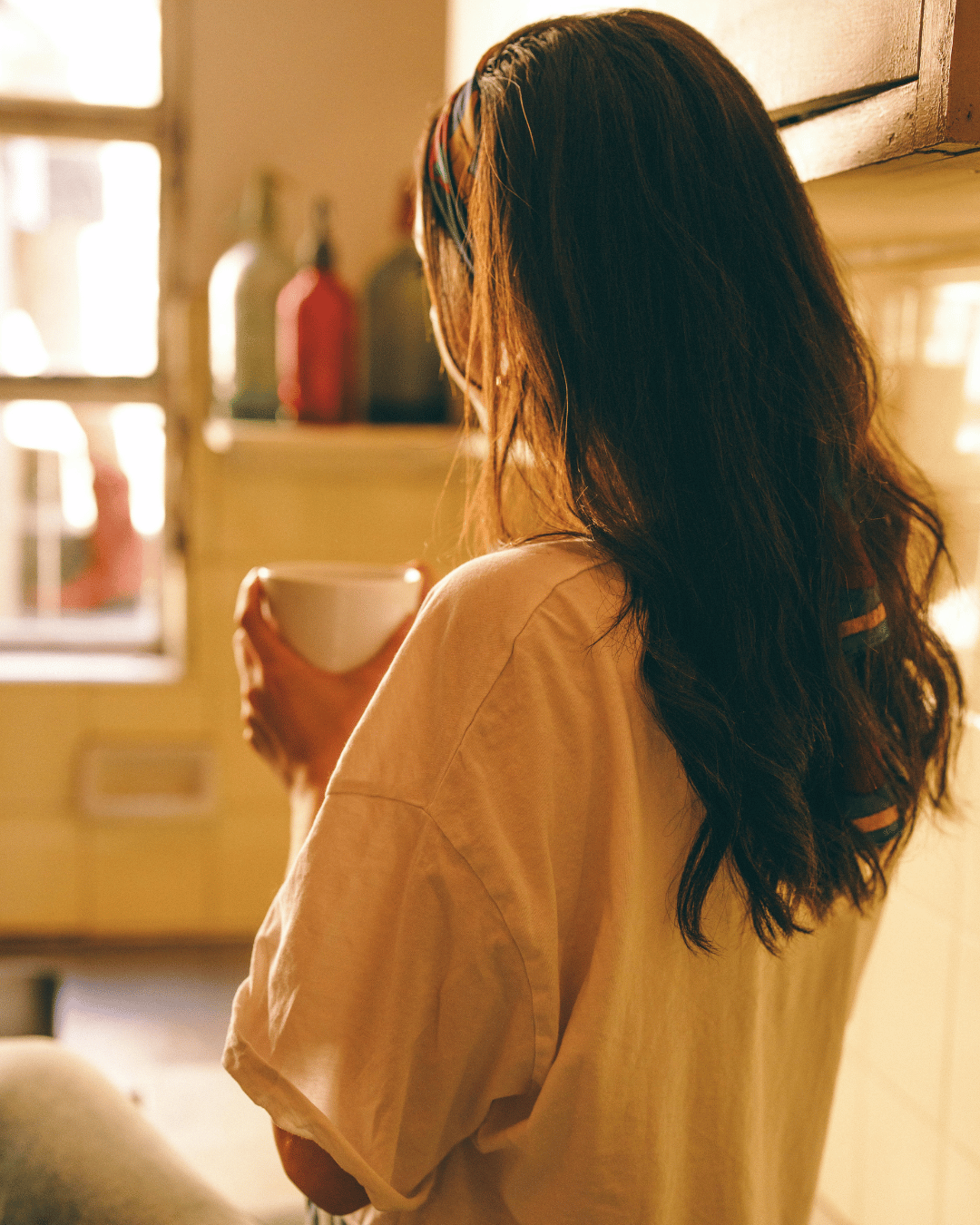Woman drinking coffee in her kitchen, preparing for her monthly recipe with the snail mail for kids club.