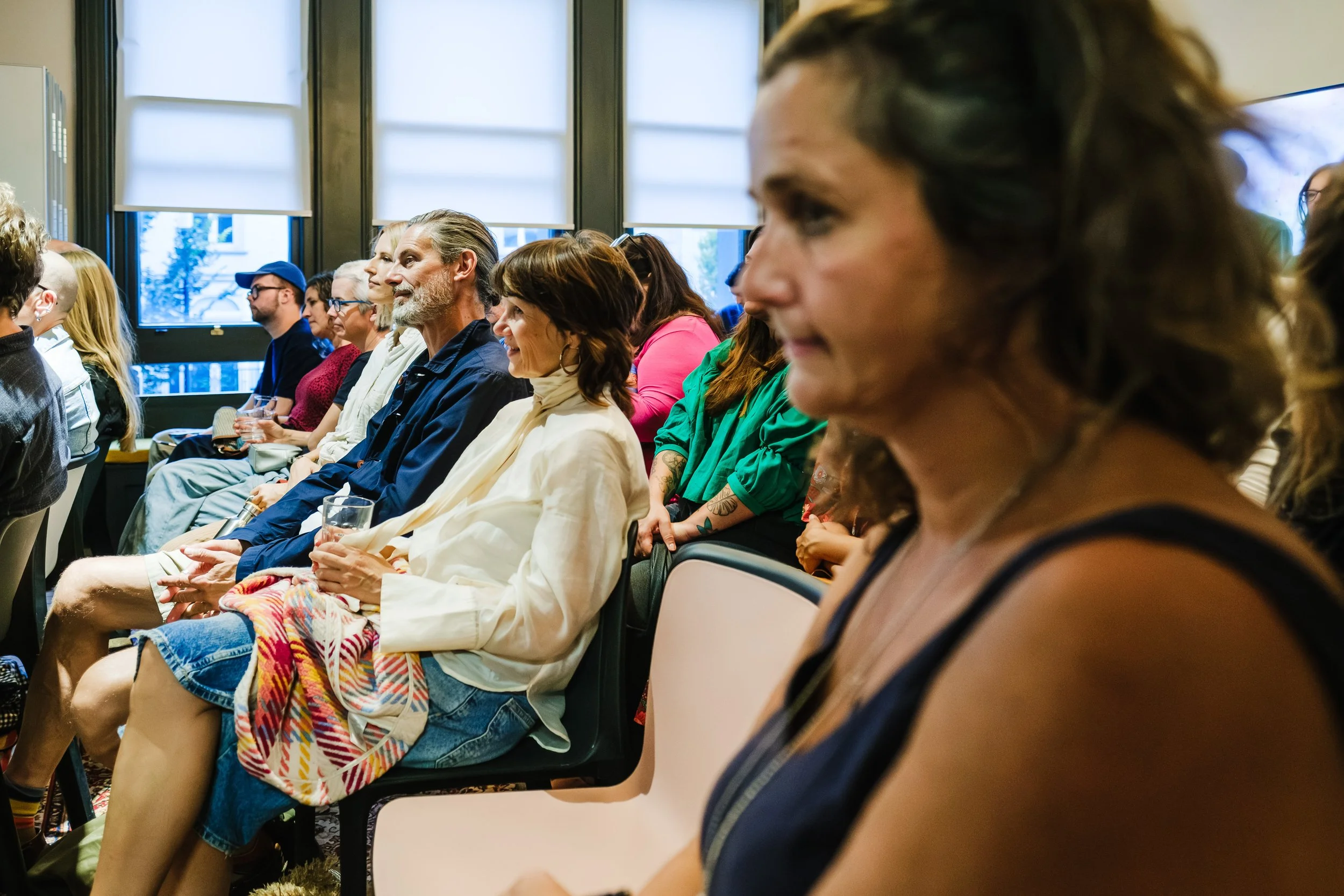 Audience of diverse adults attentively watching a presentation in a modern conference room.