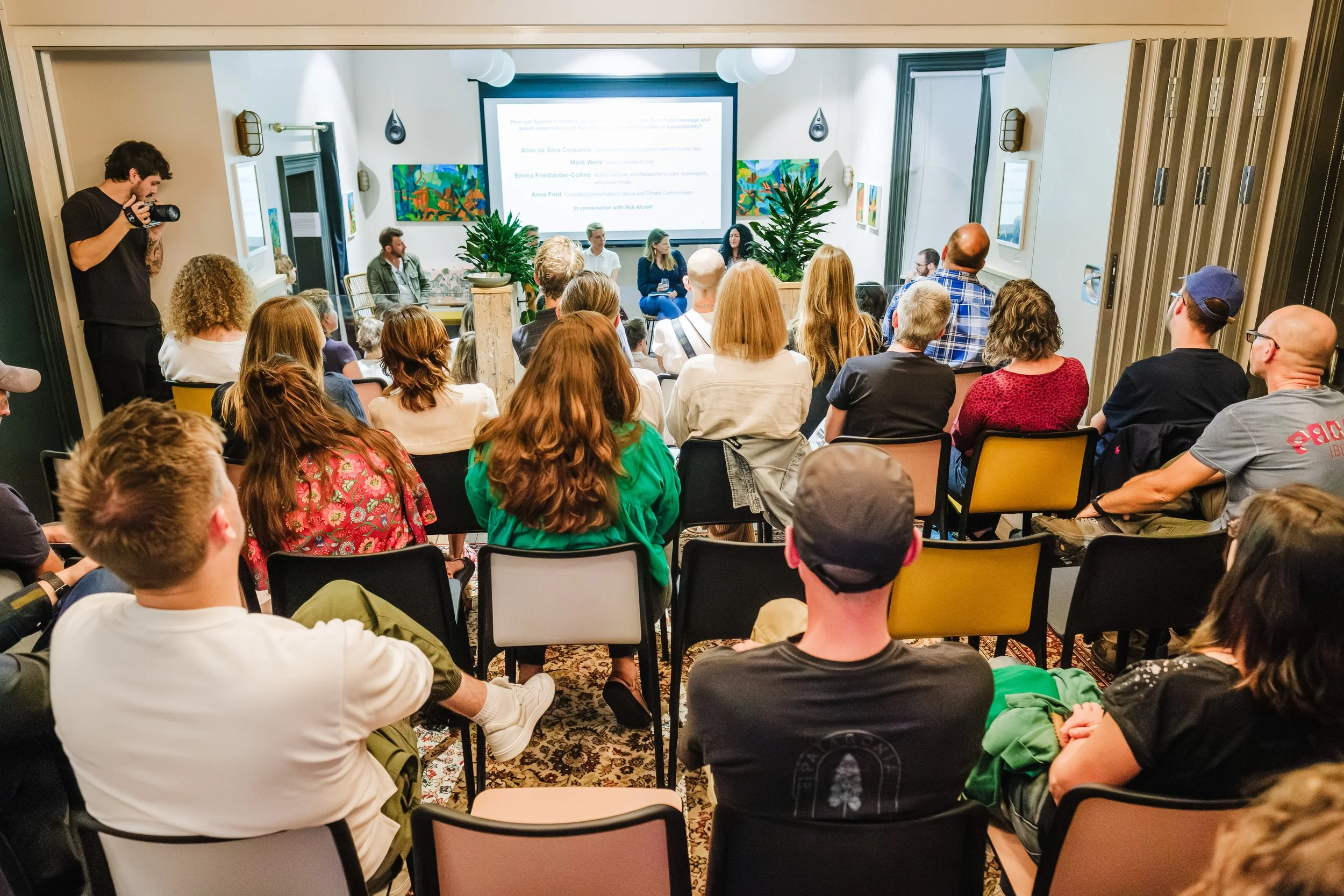Audience of diverse adults attentively watching a presentation in a modern conference room.
