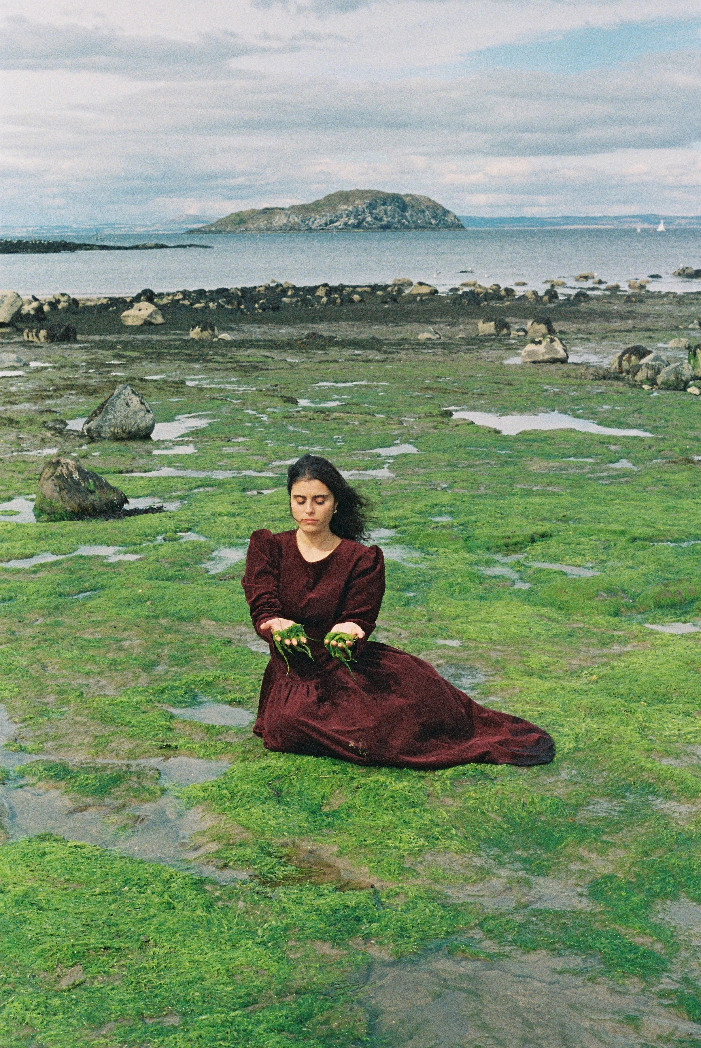 Person hanging laundry on a clothesline with a mountainous landscape in the background.