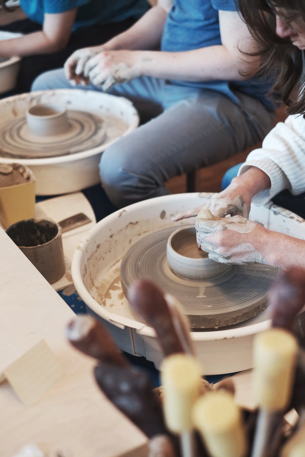 People participating in a pottery class, shaping and molding clay on spinning pottery wheels.
