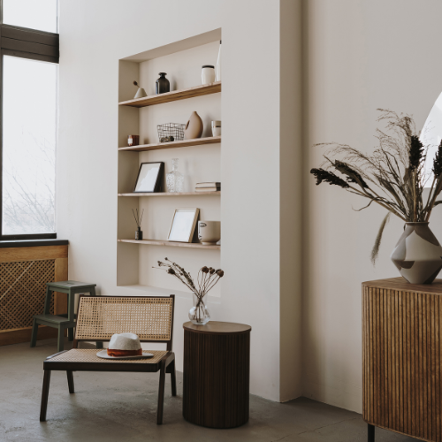 Interieur met ingebouwde witte muurkast met decoratieve spullen en een raam aan de linkerzijde, met lage meubels en vazen met droogbloemen