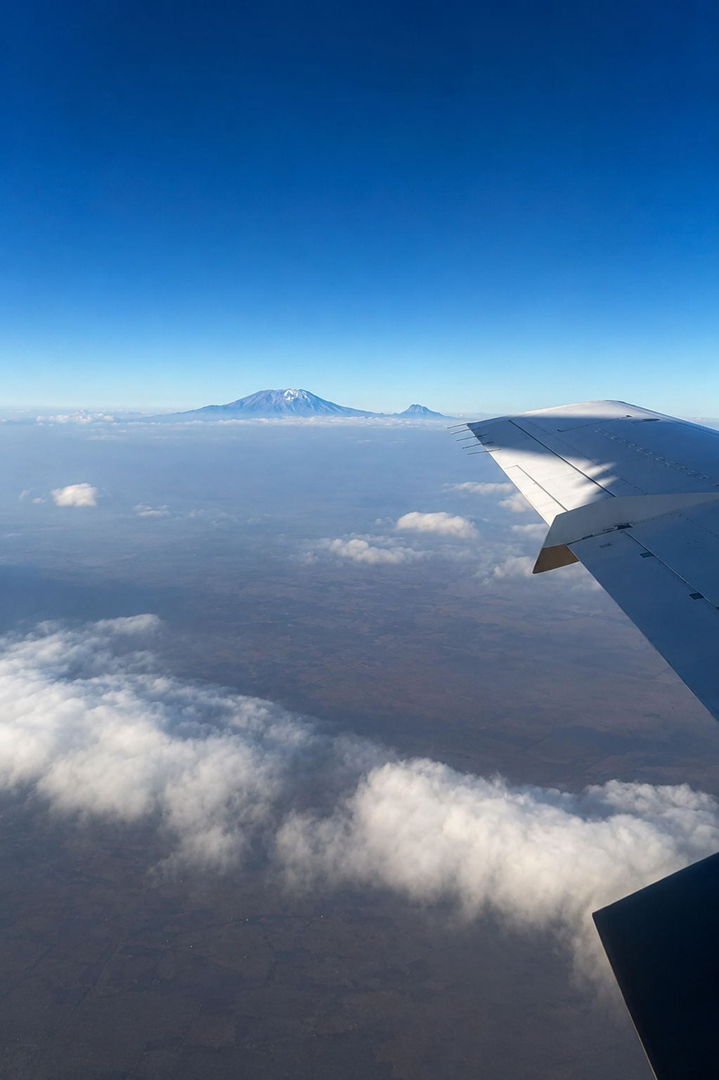 Besneeuwde top van de Kilimanjaro naast de vliegtuigvleugel tijdens onze vlucht naar Zanzibar.