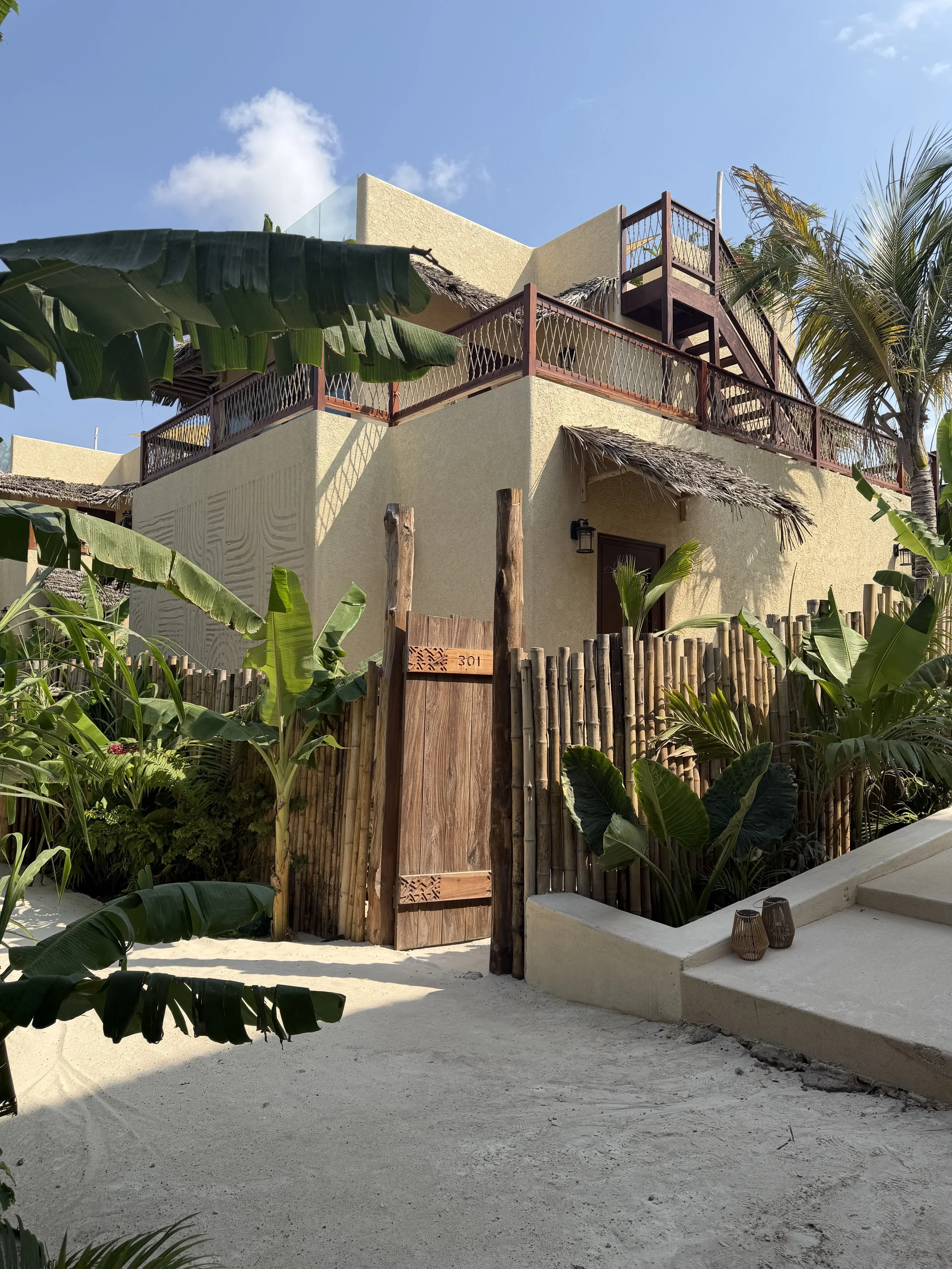 Buitenkant van de Duplex Garden Villa bij ENVI Paje op Zanzibar, met een houten toegangspoort en tropische beplanting rondom de villa.
