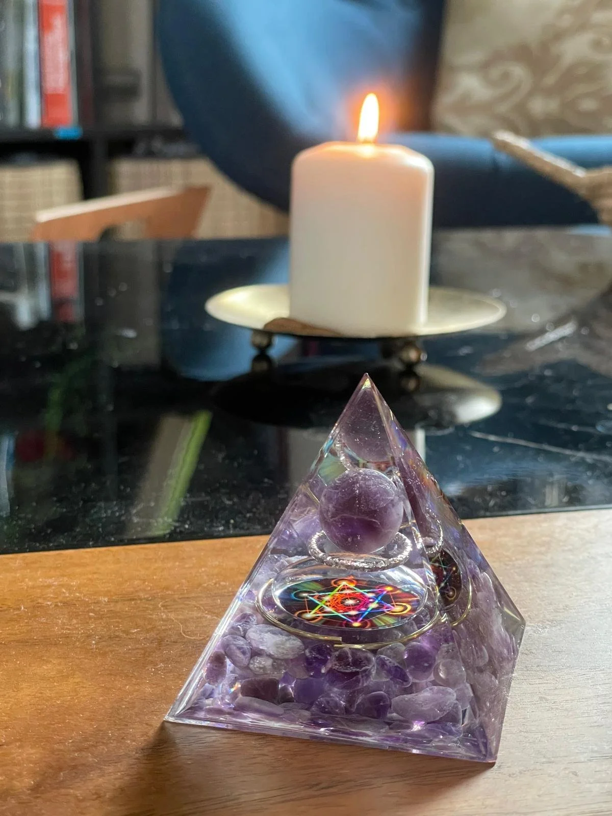 Orgonite d'améthyste sur une table de salon, à côté d’une bougie allumée pour une ambiance apaisante