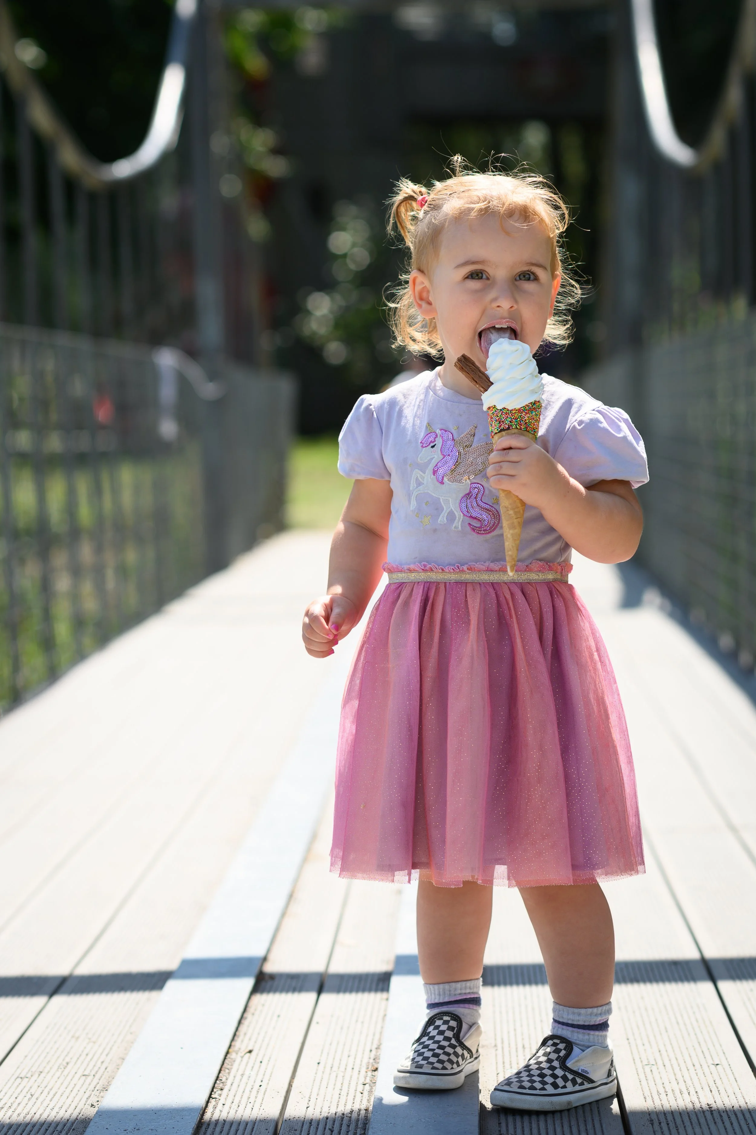Girl on a bridge licking an ice cream