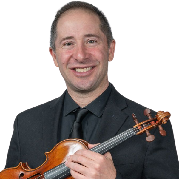 A man in a suit holding a violin while seated on a wooden chair against a dark green background.