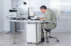 A man at a desk in his office hunching over in a non-ergonomic position.