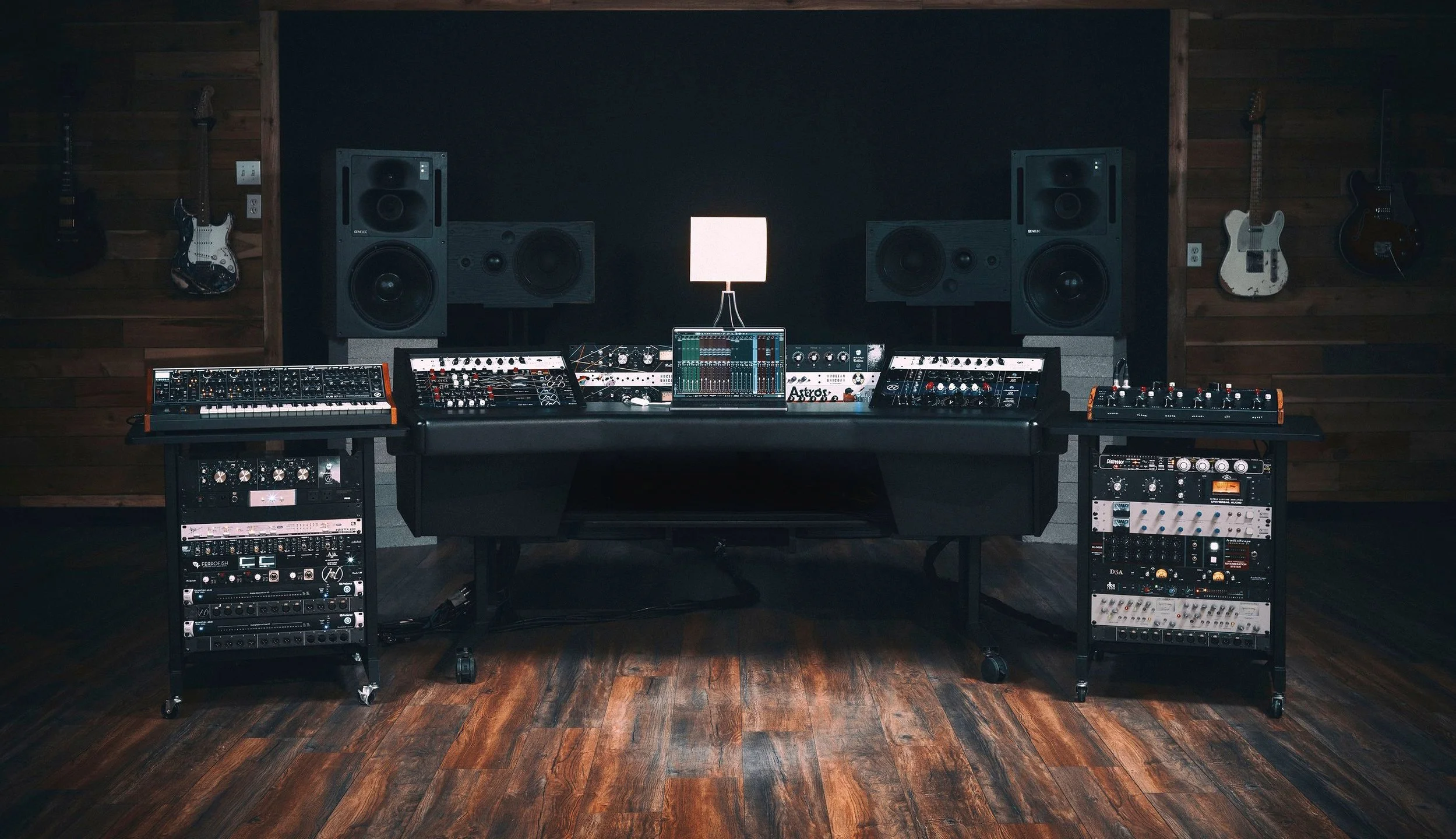 Professional music studio setup with sound mixing console, synthesizers, speakers, and electric guitars on wooden walls.