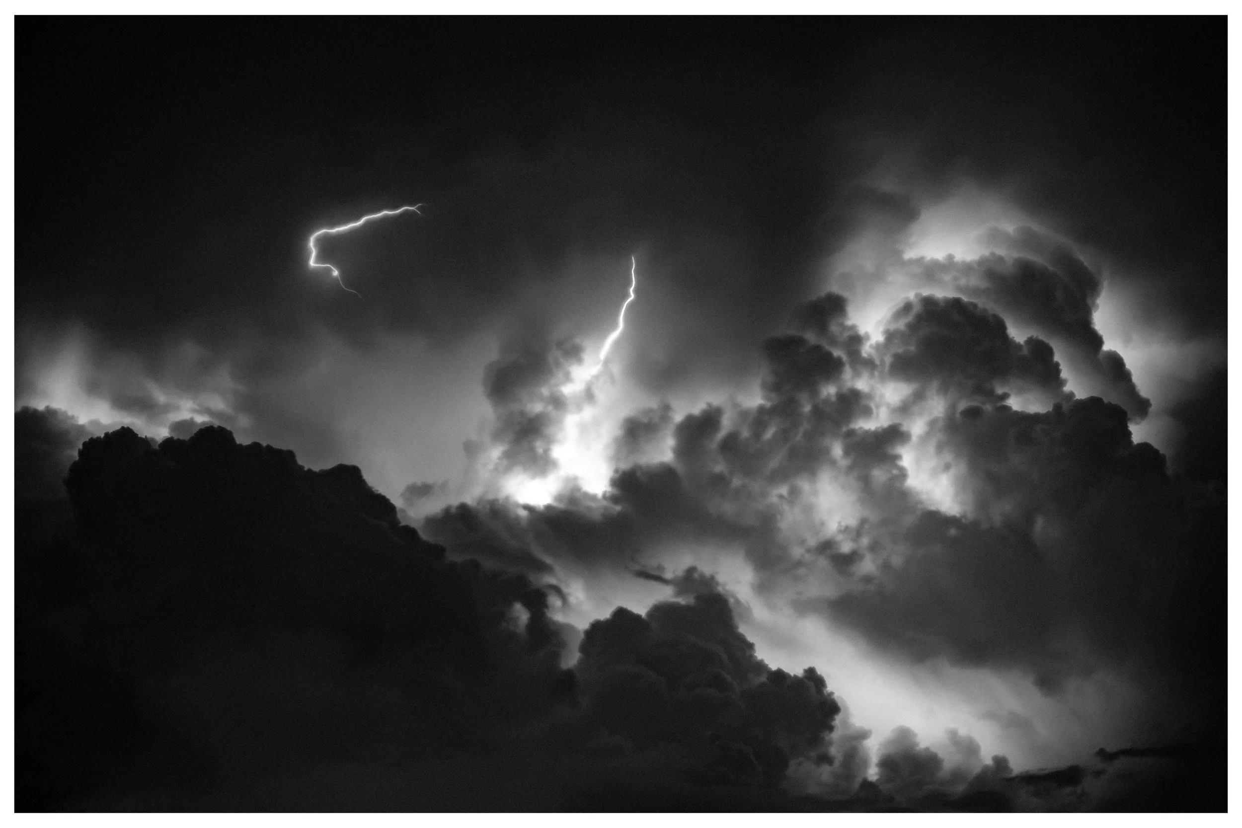 Dark, stormy clouds with visible lightning strikes in the night sky.