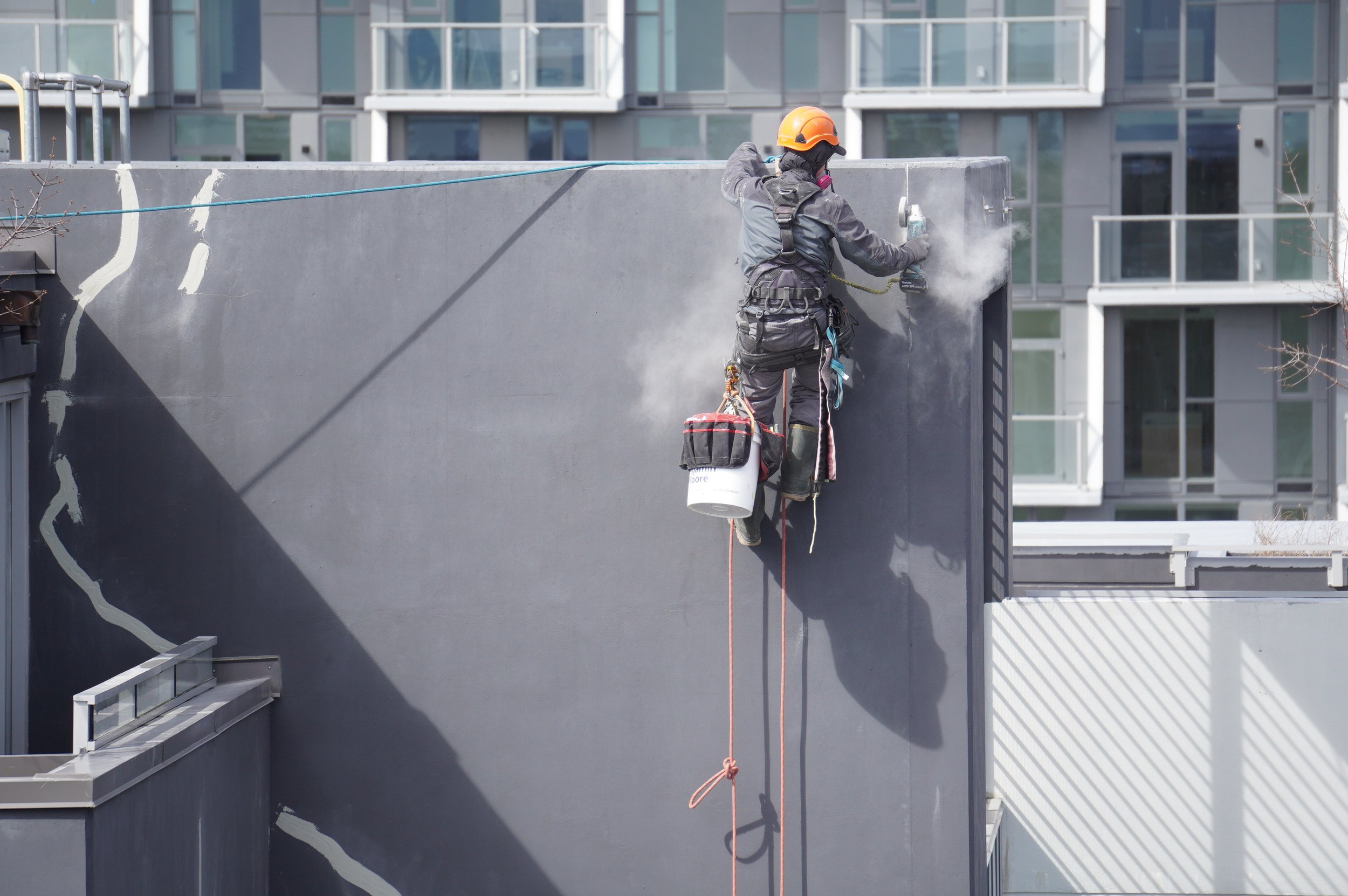Rope access technician repairing a concrete wall.