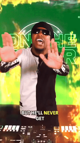 A man wearing sunglasses and a black-and-white jacket in front of a vibrant green and yellow background with neon graphics. He is gesturing with his hands and appears to be speaking or performing.