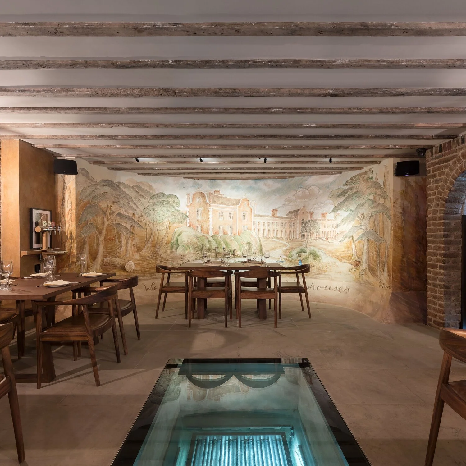 The Parlour in the basement of The Sekforde, with hand-painted frescoes, exposed brick and a glass panel in the floor