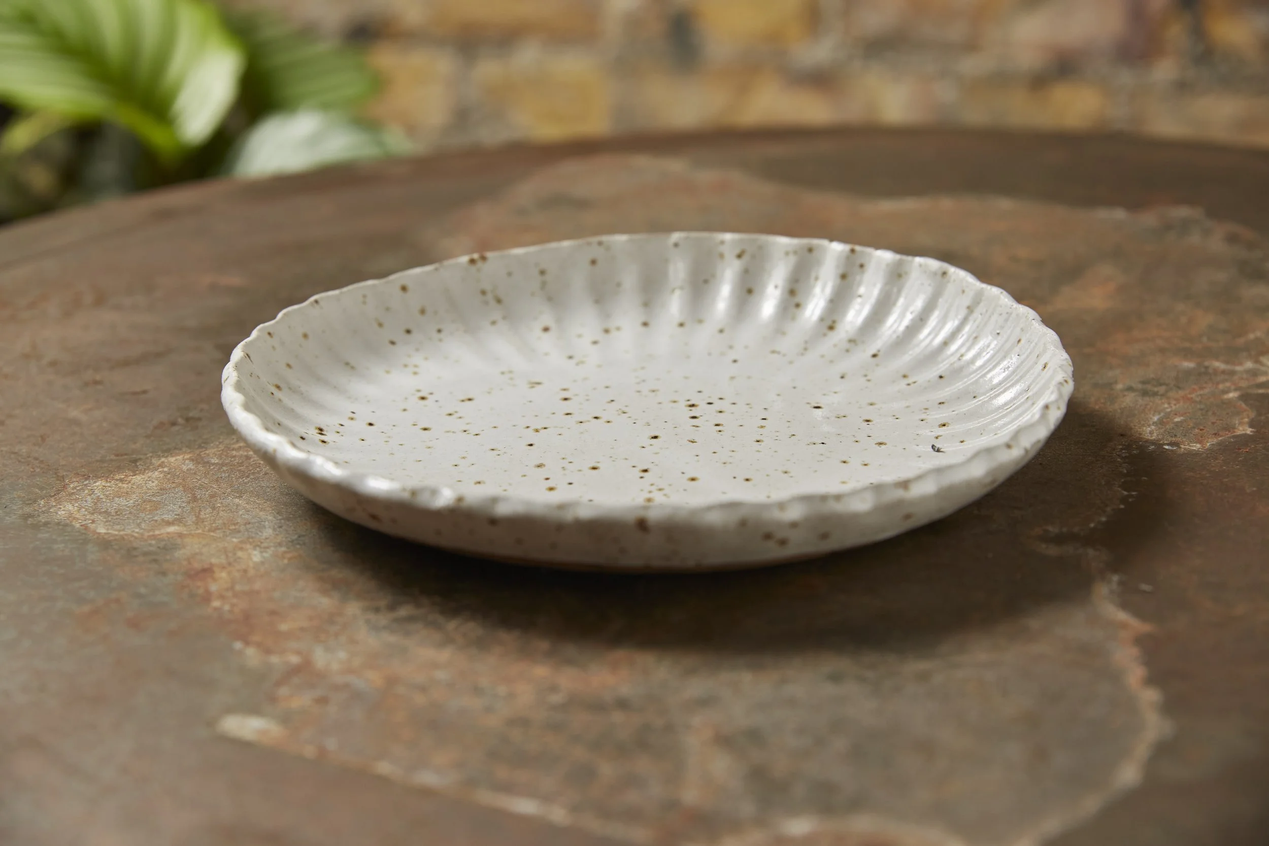 A white ceramic plate with gold speckles on a light-colored wooden surface.