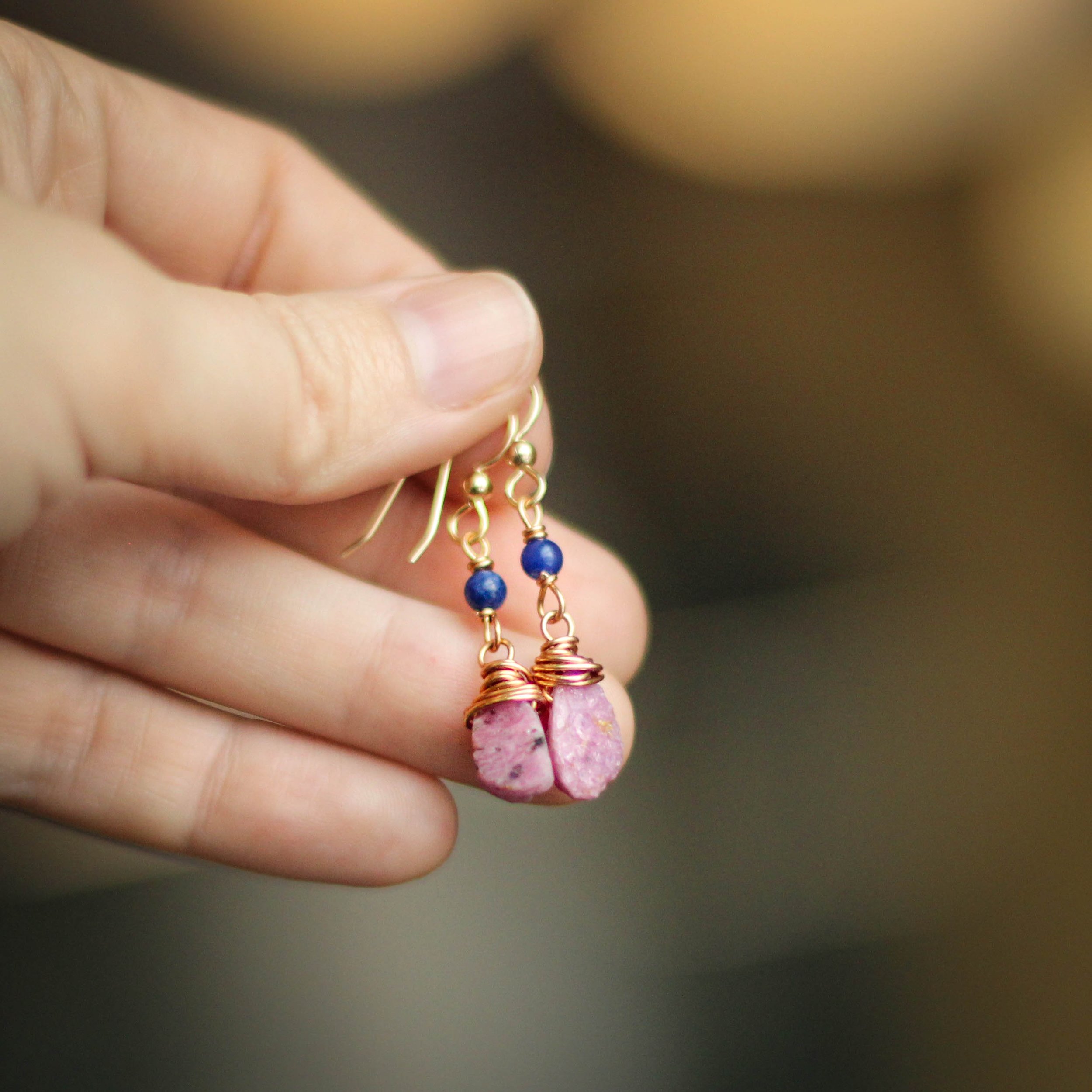 person holding ruby and sodalite earrings