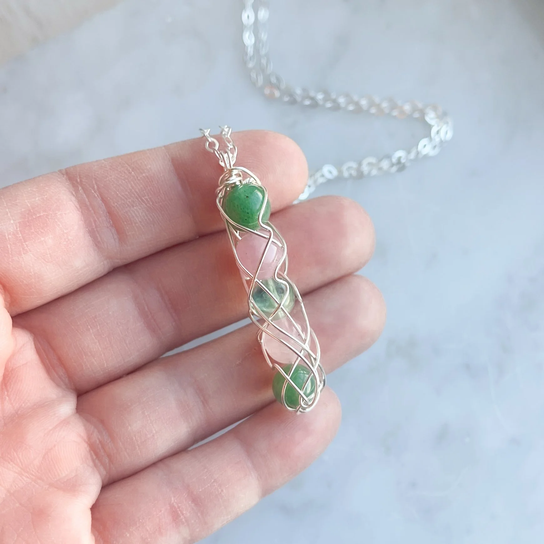 heart chakra spiral necklace in silver in hand.JPG