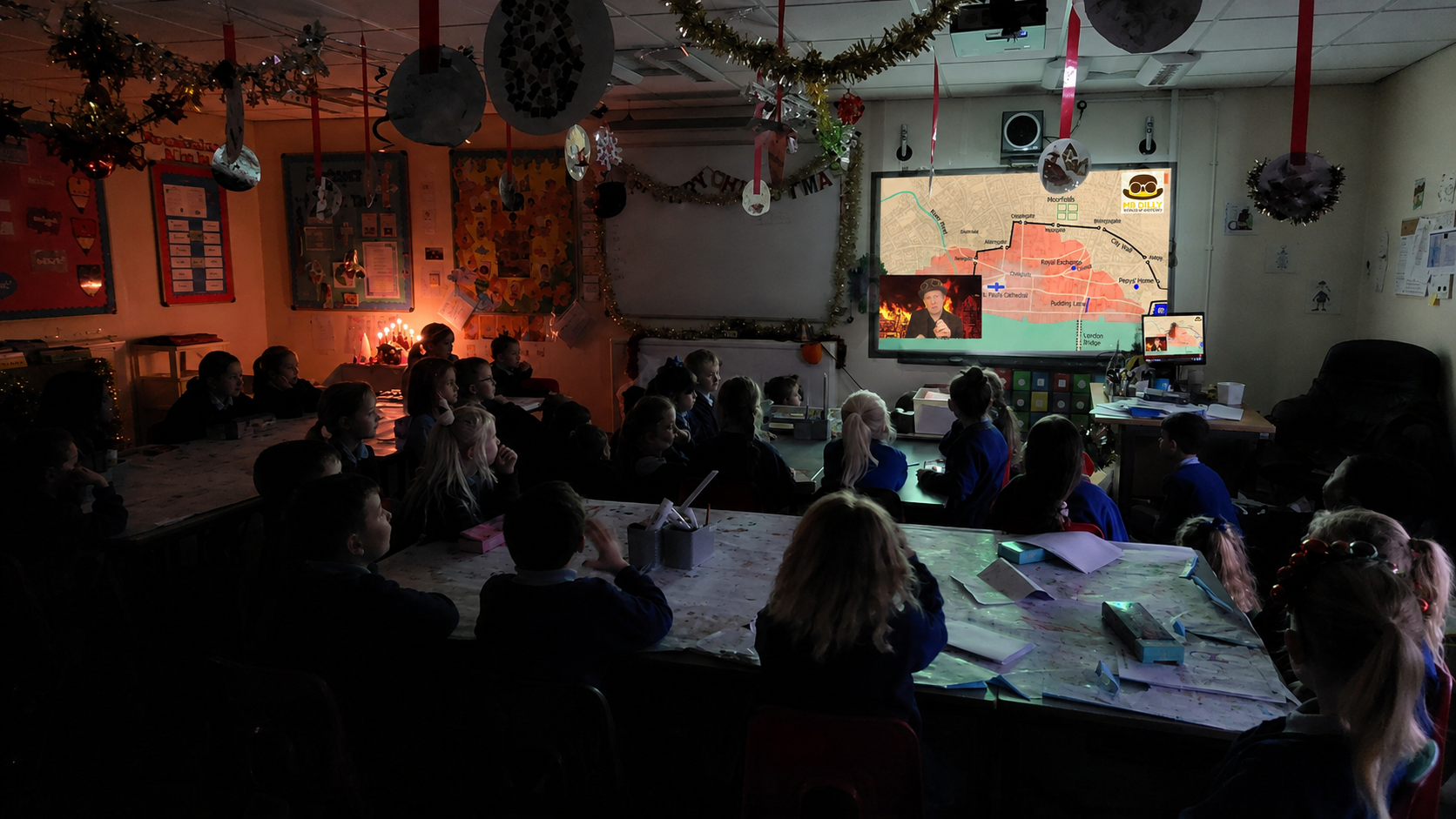 Pupils in a classroom watching Mr Dilly’s virtual Great Fire of London history visit, with a map of 1666 London and the spread of the fire displayed on screen.