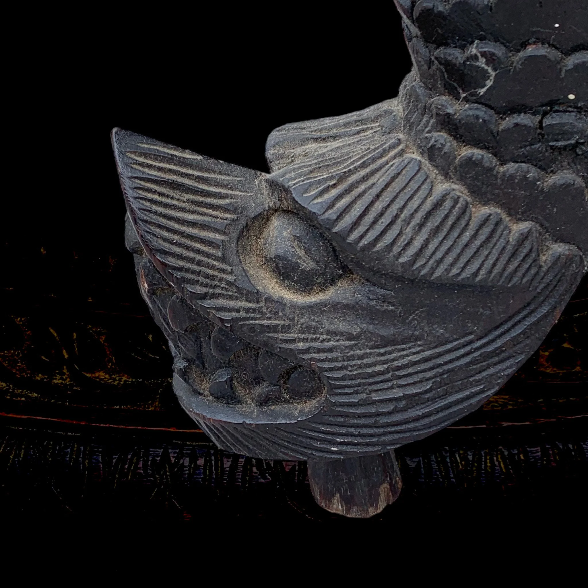 Close-up of a carved black artifact with intricate patterns and a circular detail.