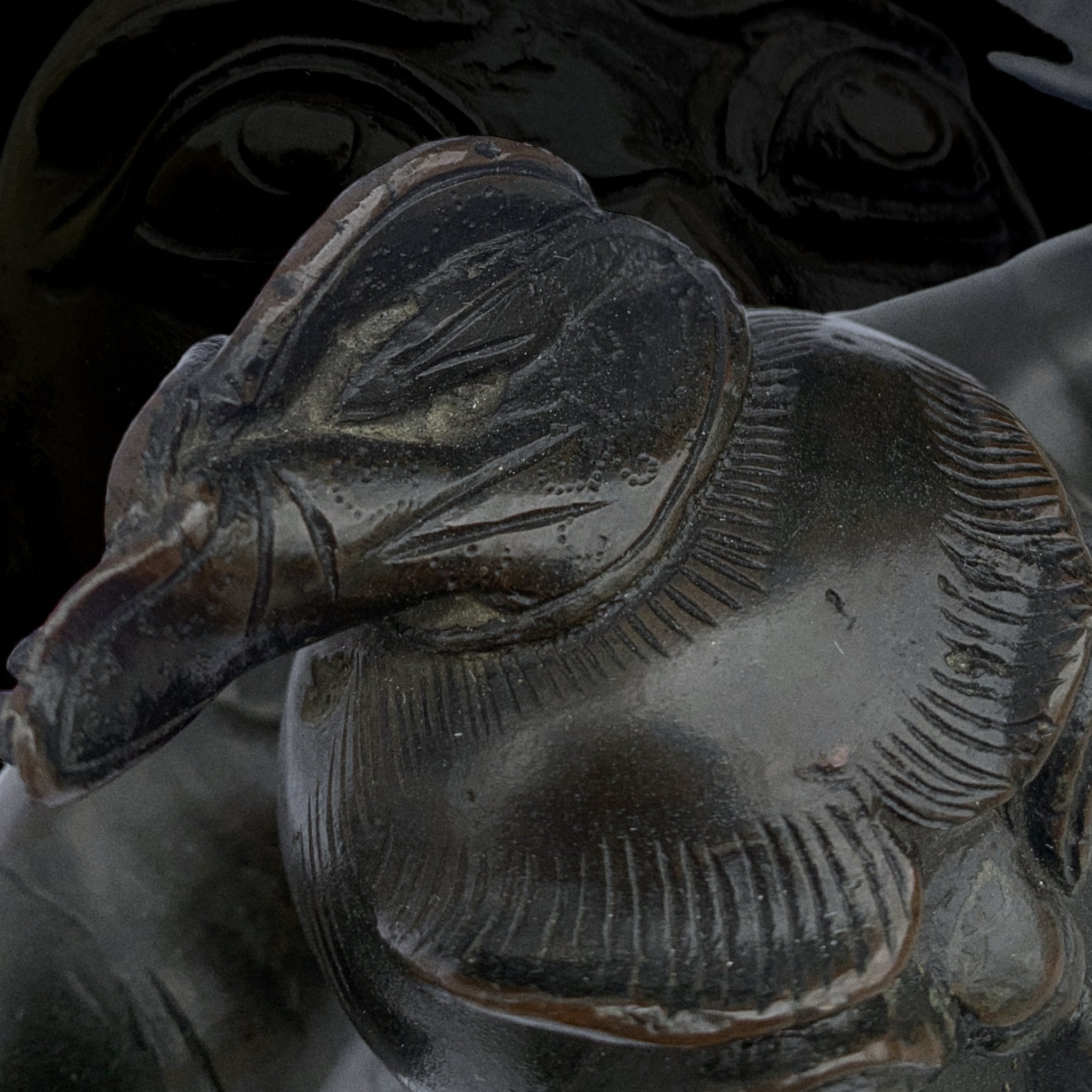 Close-up of a carved glass or crystal figurine of a bird, possibly a duck or goose, with intricate feather details.