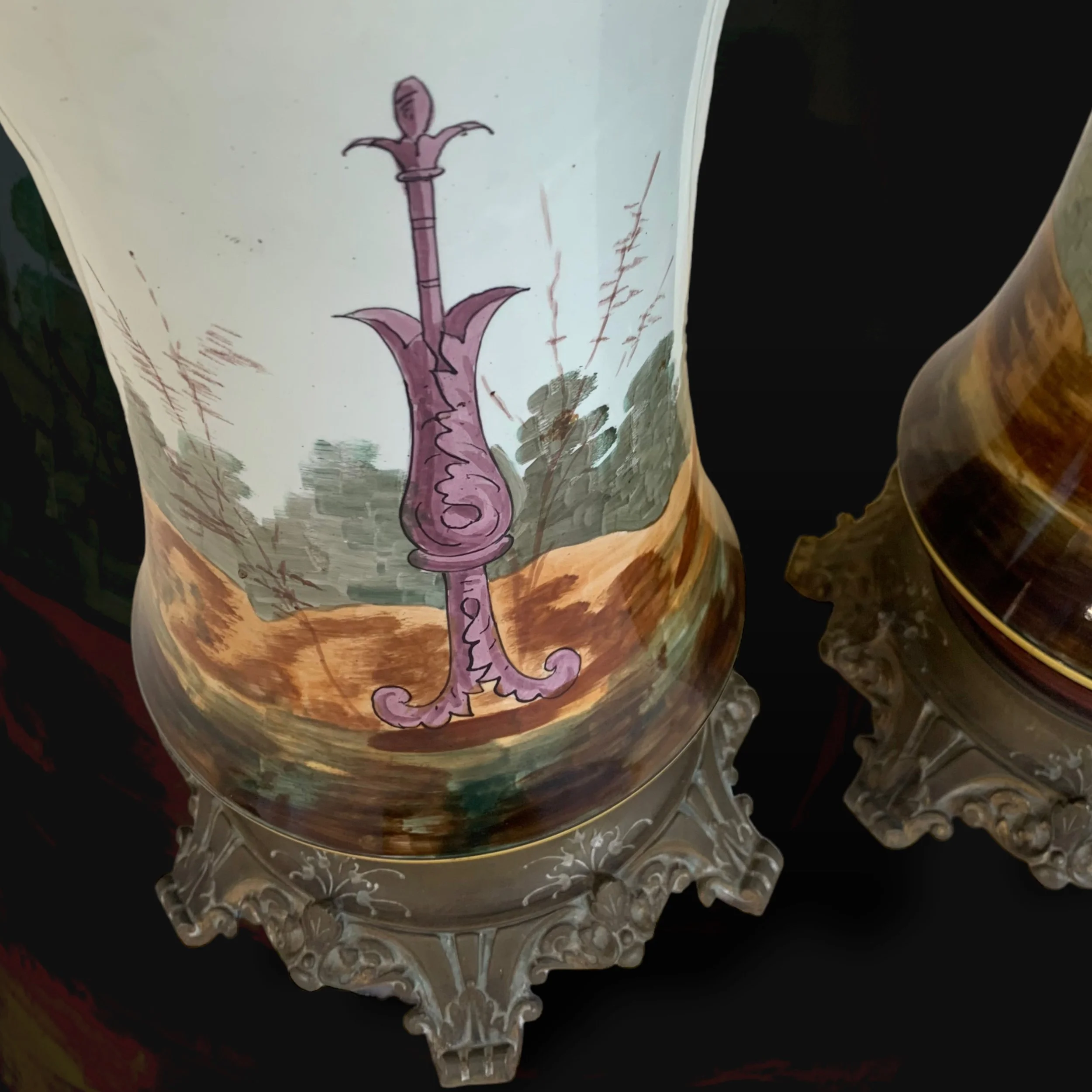 Decorative porcelain object with a painted landscape scene and a pink, ornate sword design on it.