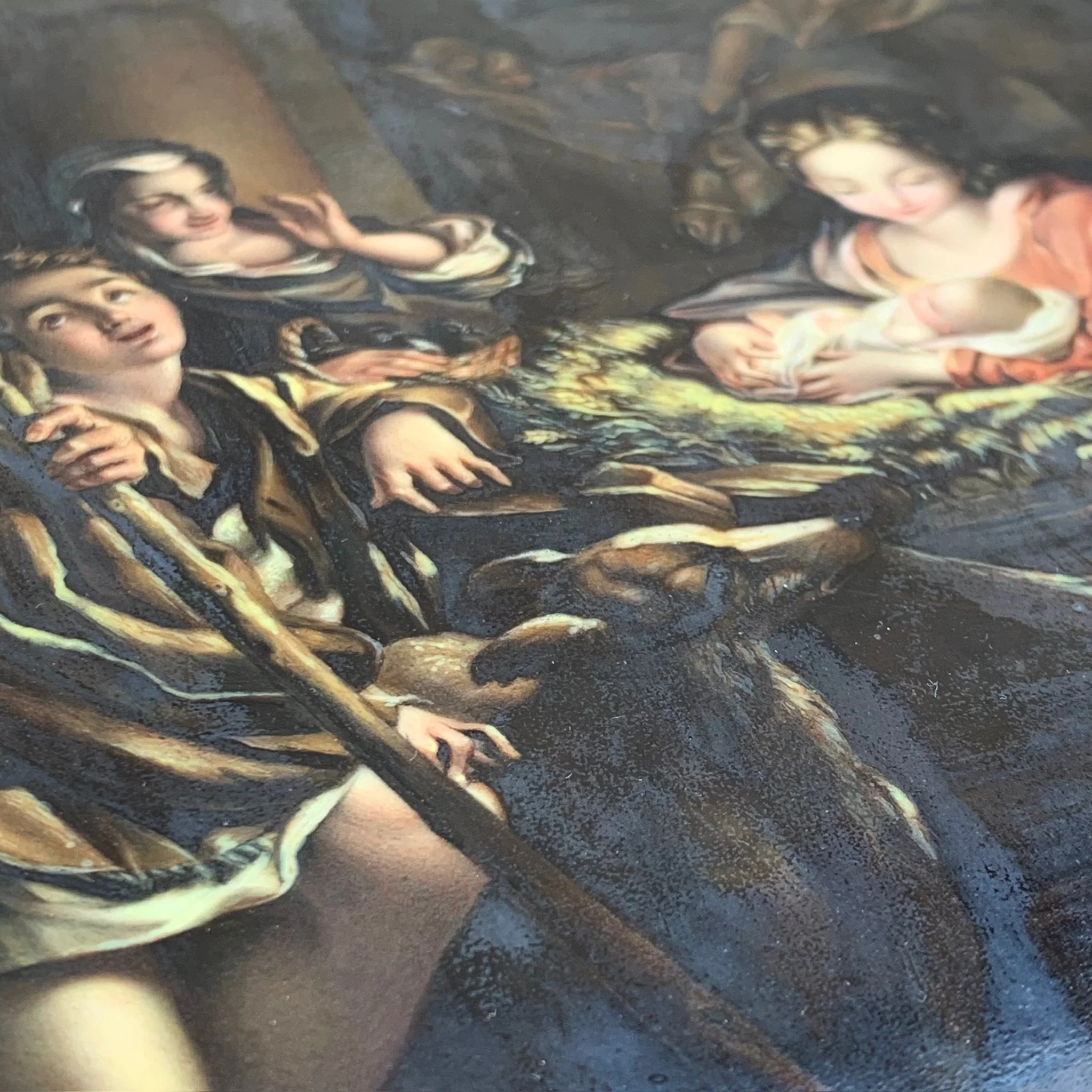 Close-up of a painting depicting a religious scene with women, children, and a lamb, using dark and warm colors.