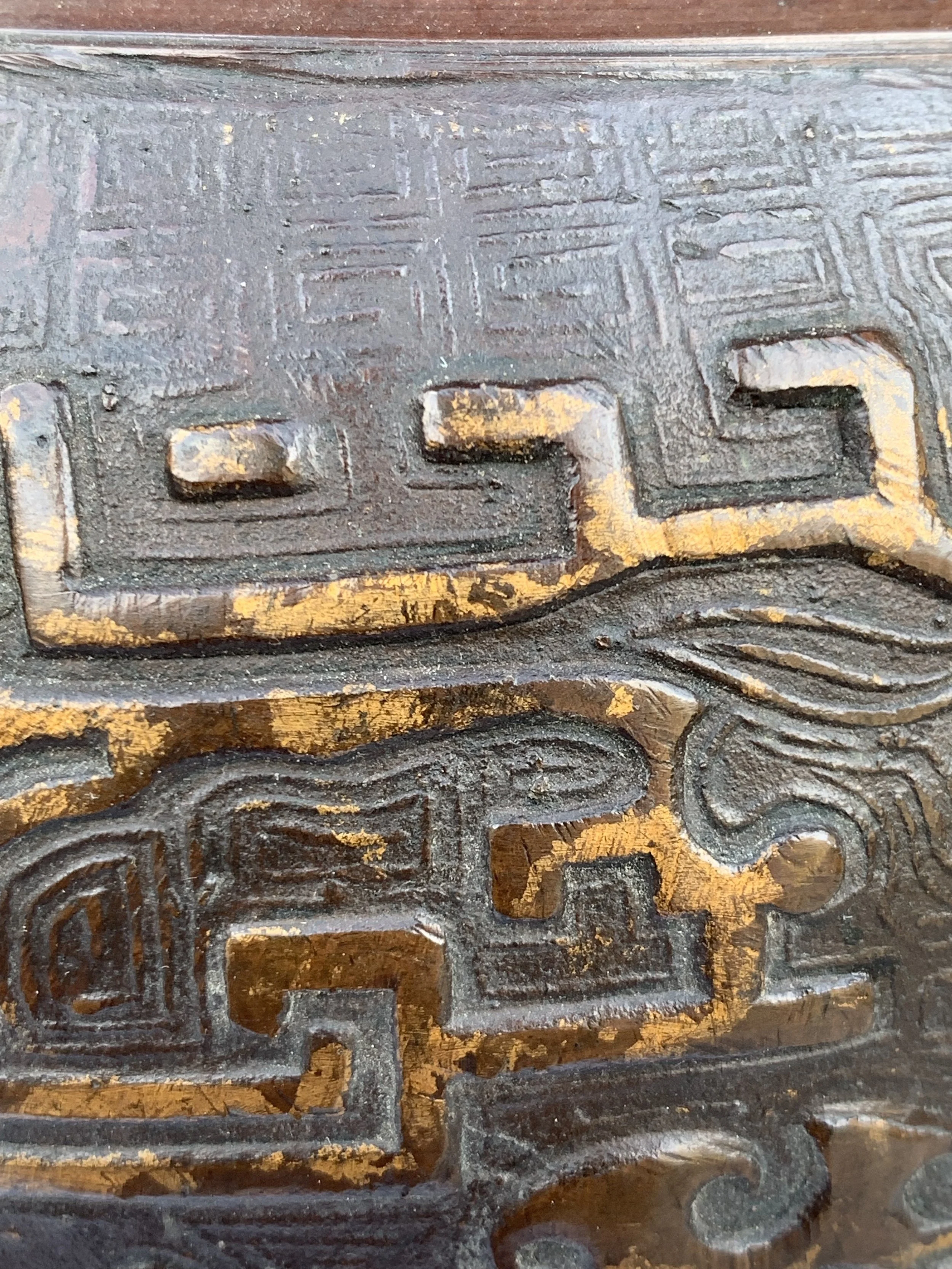 Close-up of an intricately carved metallic surface with geometric and abstract patterns, some areas with a gold color finish.
