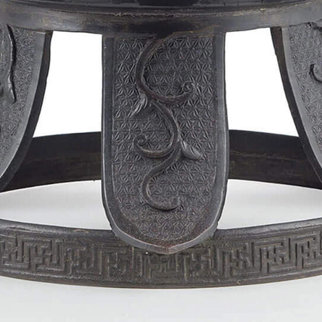 Close-up of a carved dark wood circular decorative band with intricate geometric and vine patterns, featuring a central vertical panel with a carved vine motif.