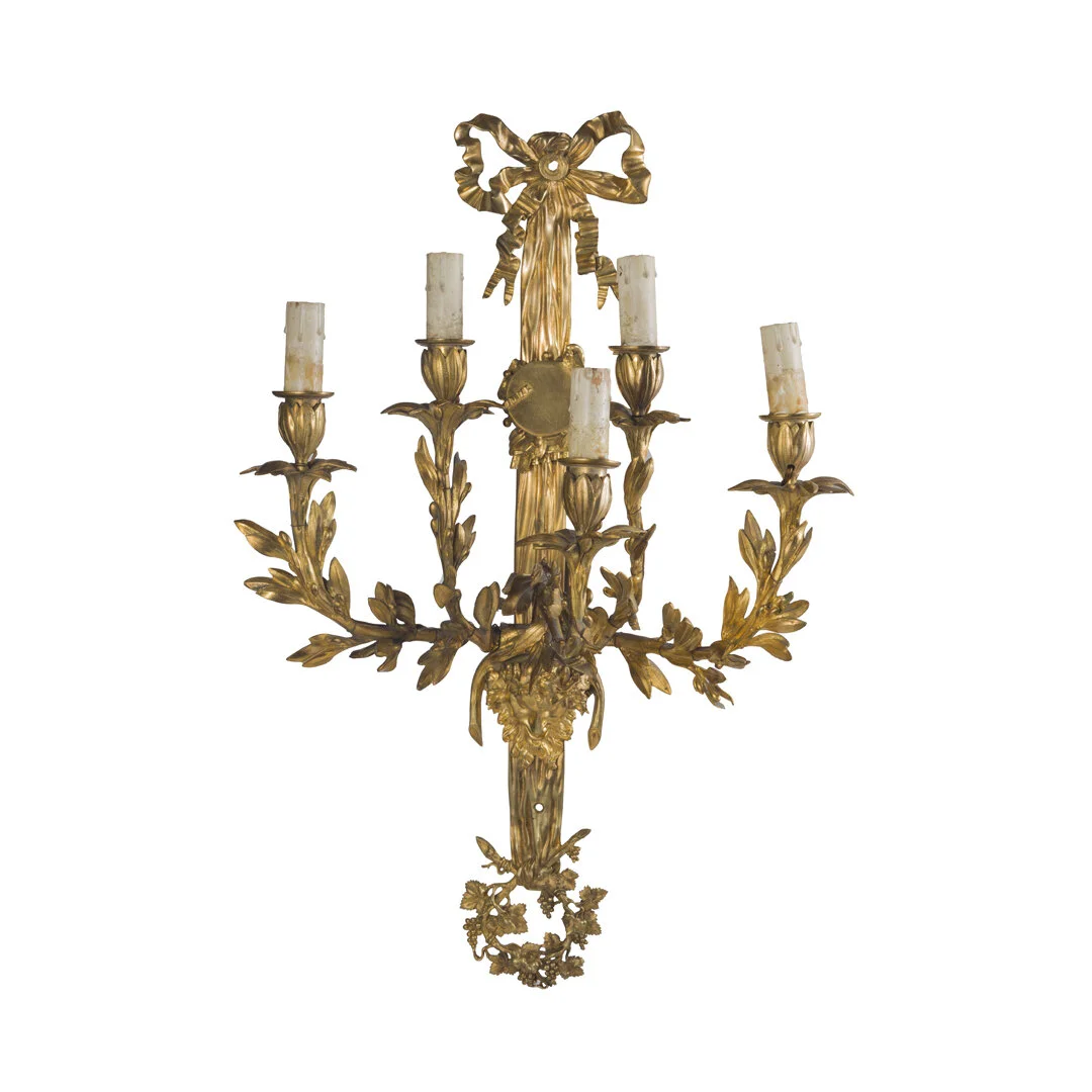 Gold ornate wall sconce with five candle holders and a decorative bow at the top.