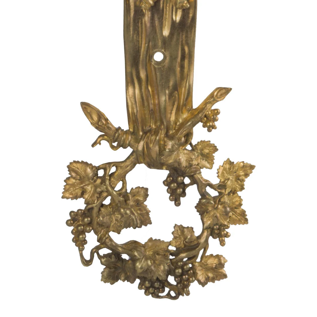 Gold-colored decorative brass wall piece featuring grapevine motif with leaves and grapes.