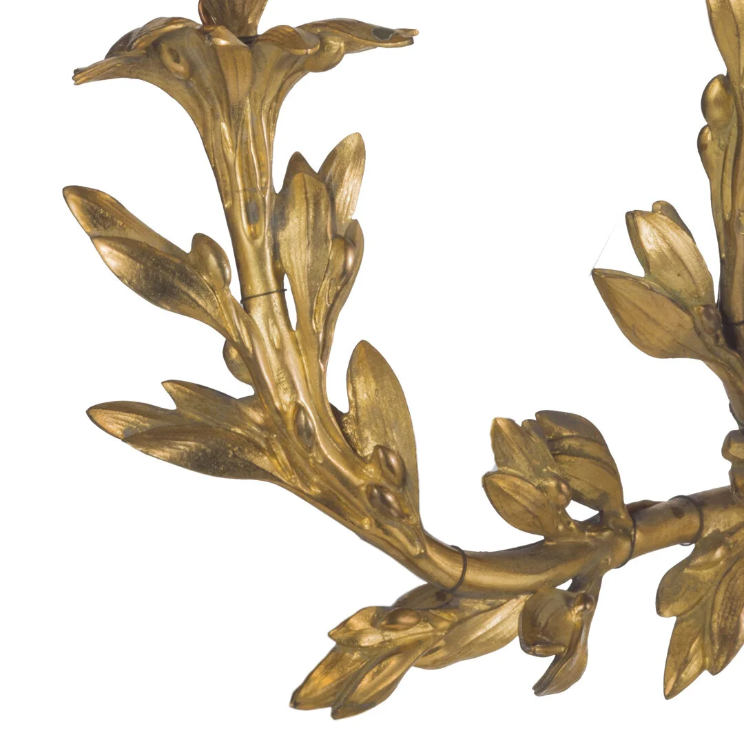 Close-up of a decorative gold-colored leaf motif wall sconce or ornament with intricate detailing.