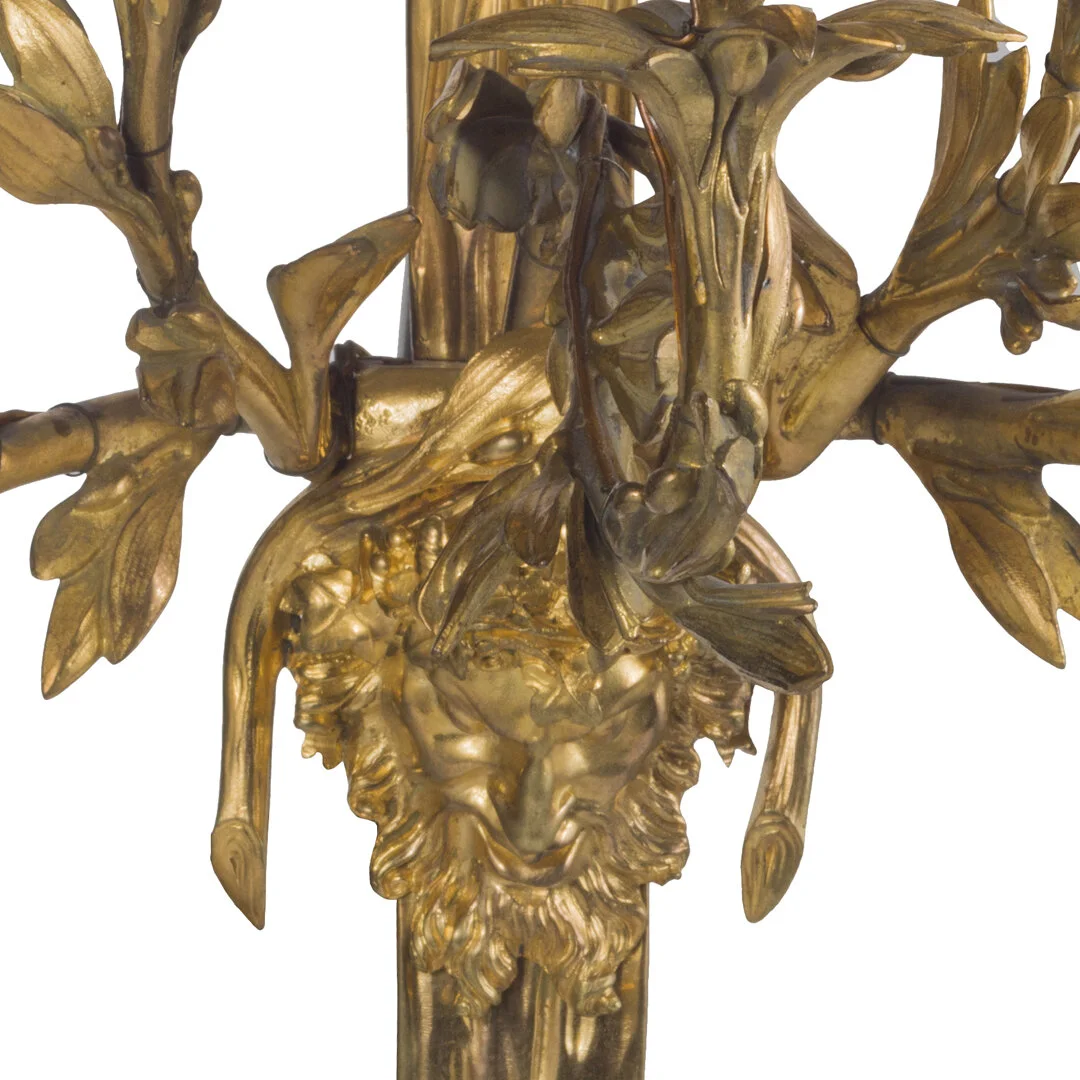 Close-up of an ornate gold sculpture featuring a lion's face with a crown of leaves and branches.