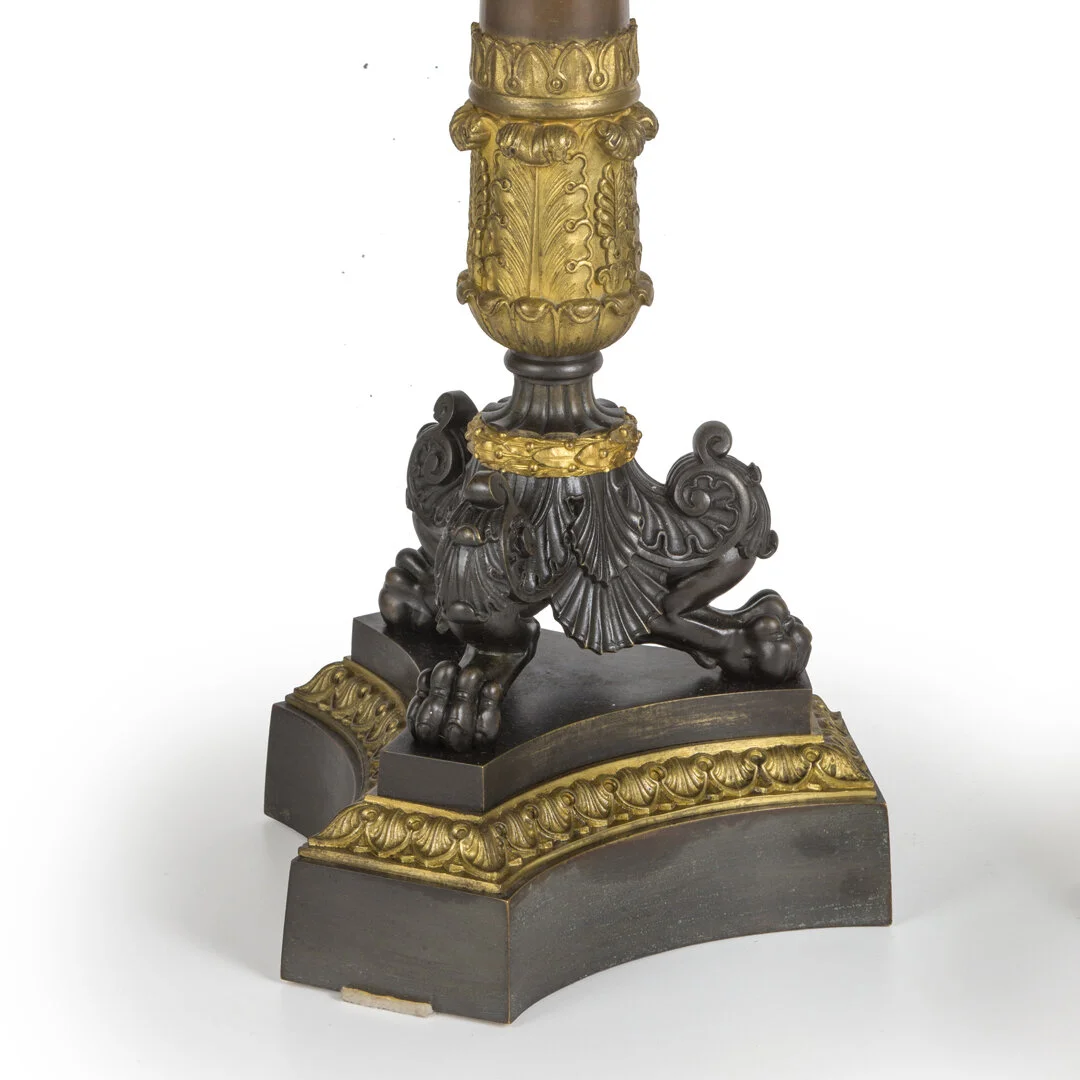 Close-up of a decorative table or lamp base with ornate gold and black detailing, featuring a lion's paw at the bottom.
