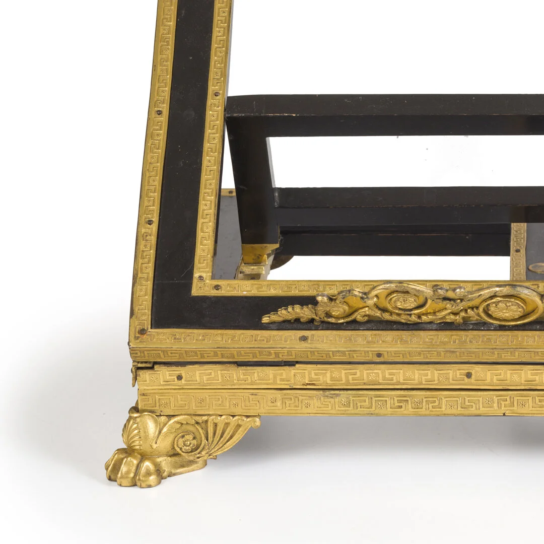 Close-up of an ornate black and gold antique table corner with decorative detailing and clawfoot design.