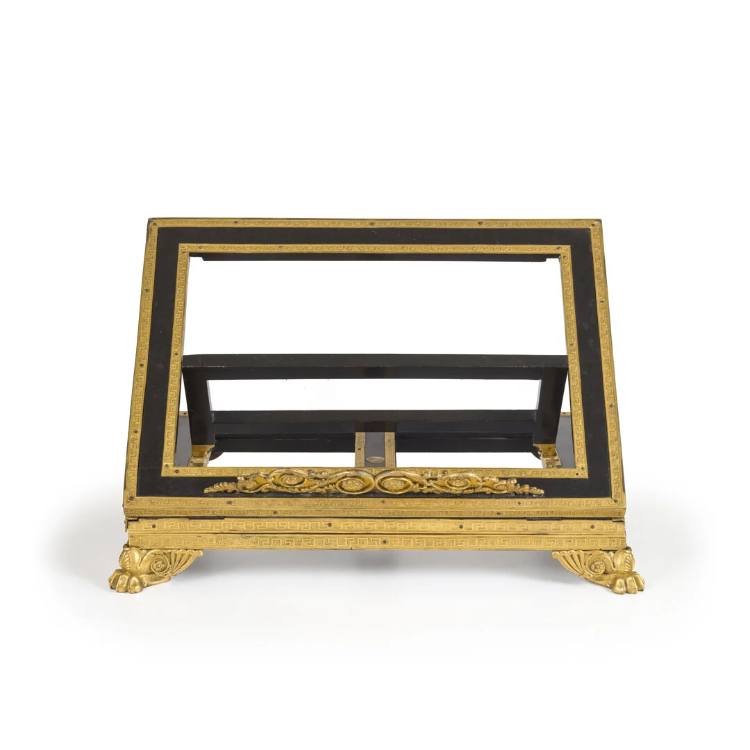 A decorative black and gold picture frame stand with ornate gold details and four gold feet, designed to hold a photograph or artwork.