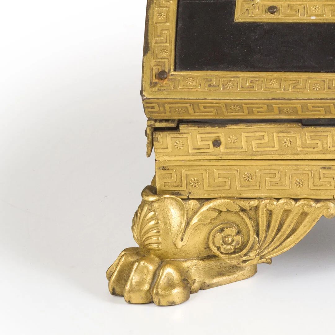 Close-up of ornate gold-colored base of an antique object with decorative patterns and a paw-like foot.