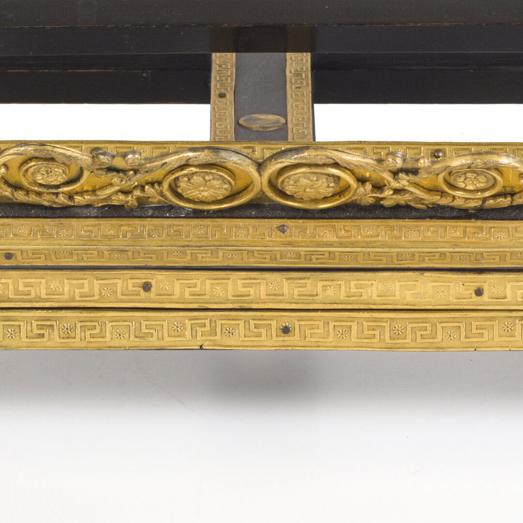 Close-up of ornate gold decorative trim with floral and geometric patterns, part of a piece of furniture or artwork.
