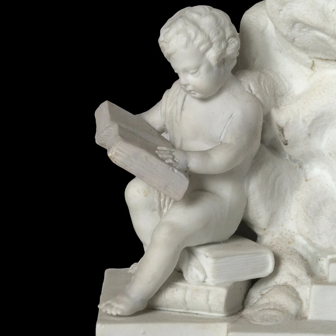 White marble sculpture of a young boy reading a book, sitting on a bench with additional books around him, against a black background.