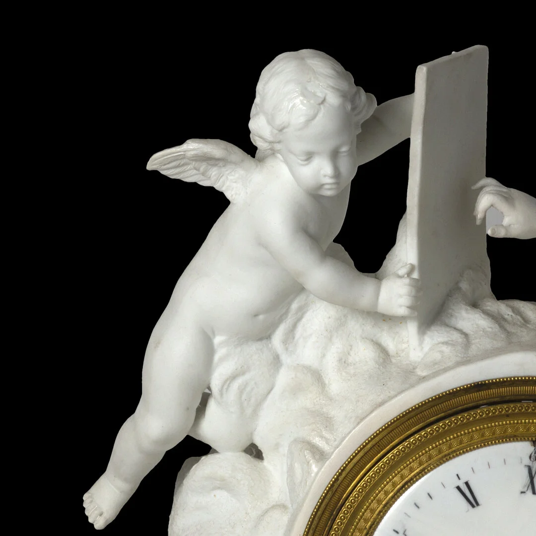 A white cherub sculpture with wings, leaning on a cloud-like base, partially visible clock face with Roman numerals in the bottom right corner.