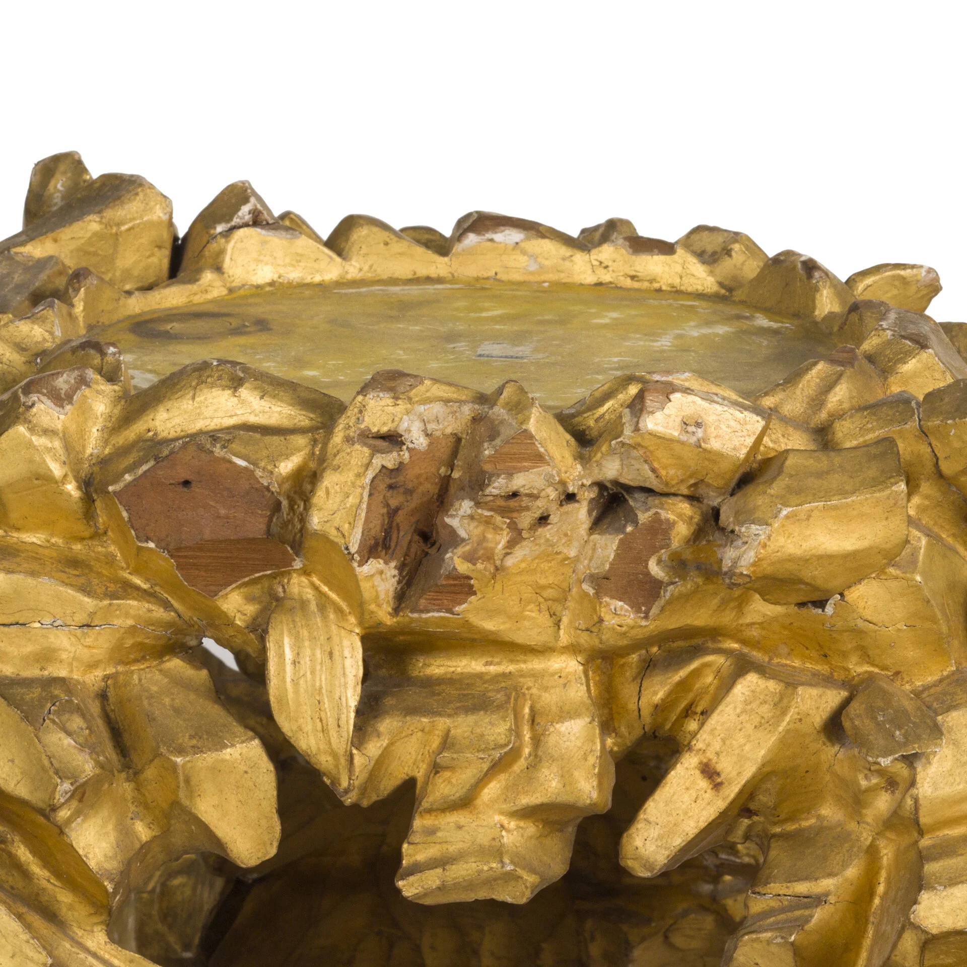 Close-up of a gold ornate decorative object with a flat surface on top, featuring chipped paint and a textured design resembling a leafy wreath.