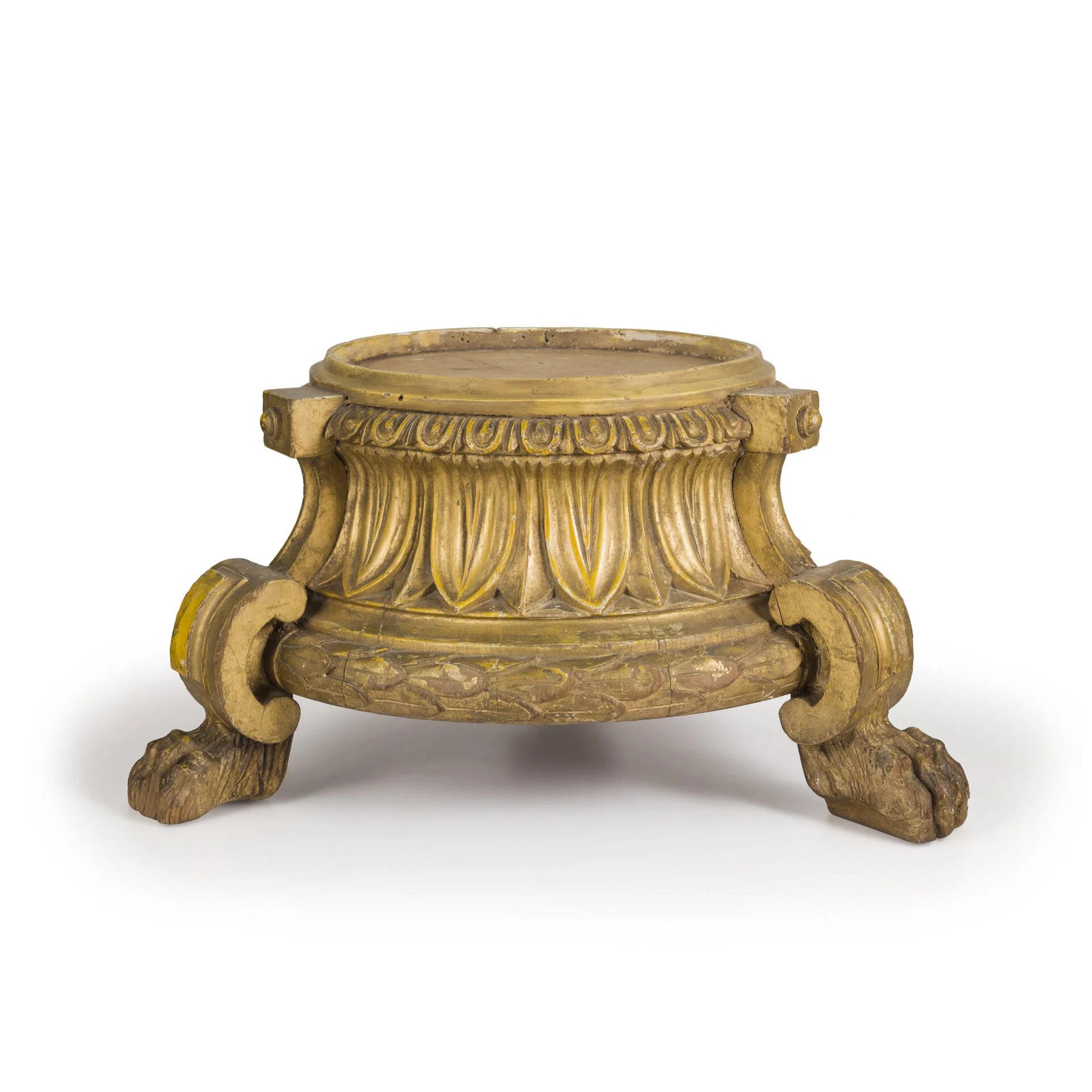 Antique gold-colored carved wooden stand with decorative floral and scroll motifs, raised on three curved, paw-like feet.
