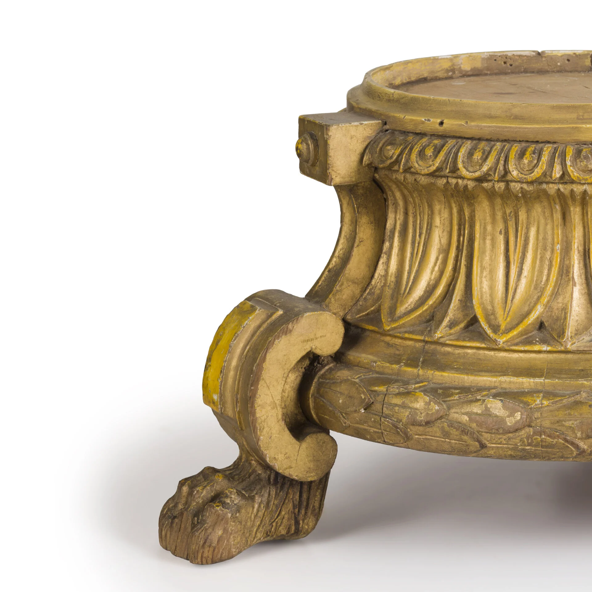 Close-up of an ornate, antique gold-colored wooden furniture leg with carved details and a clawfoot design.