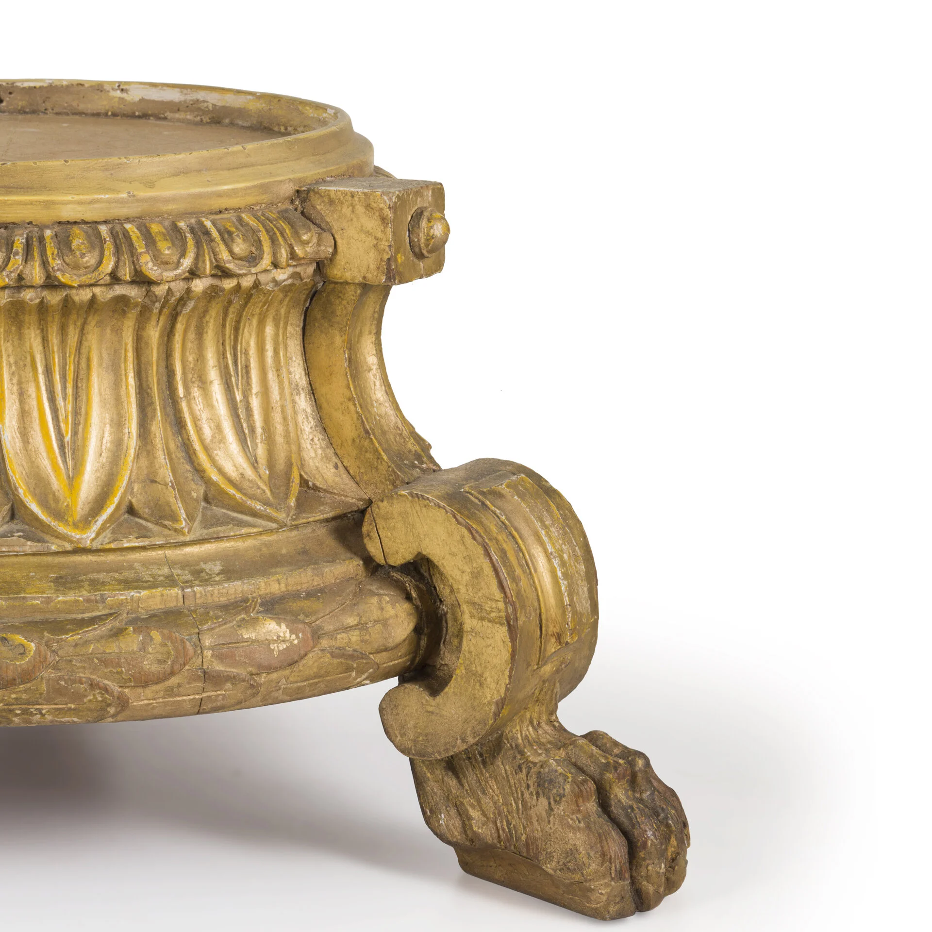 Close-up of an ornate, gold-colored carved wooden furniture leg with intricate floral and leaf details.