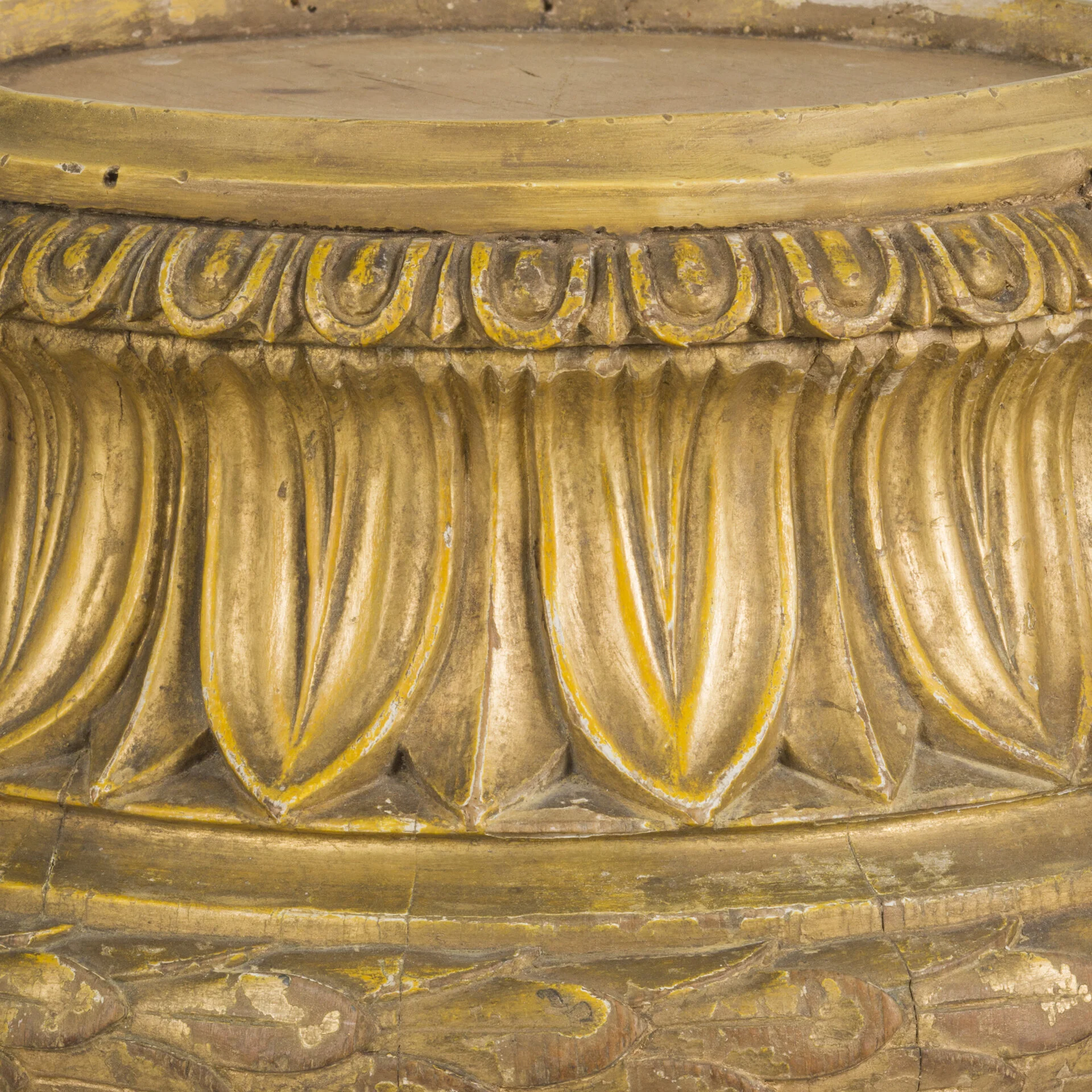 Close-up of a carved and gilded wooden decorative element with a repeating pattern of leaf shapes and ornate detailing.