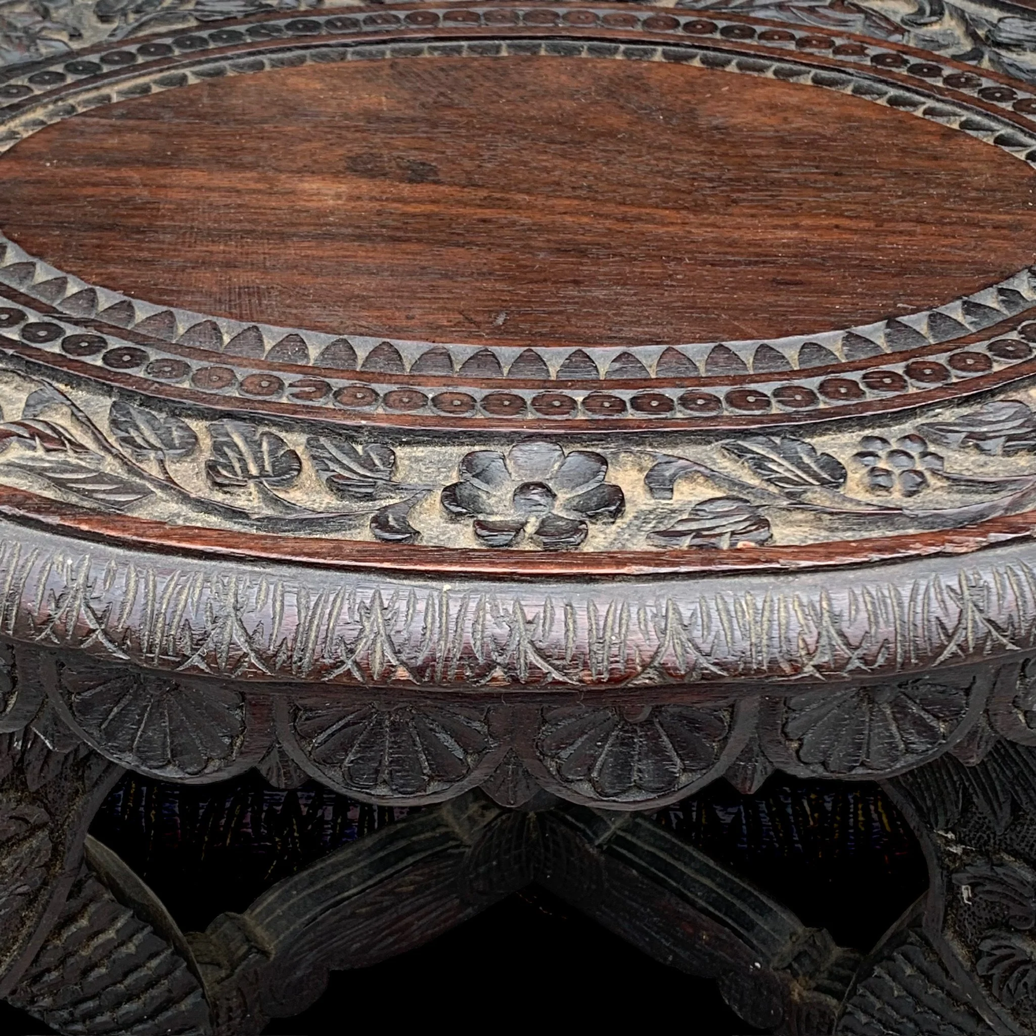 Close-up of an intricately carved wooden table with floral and geometric patterns.