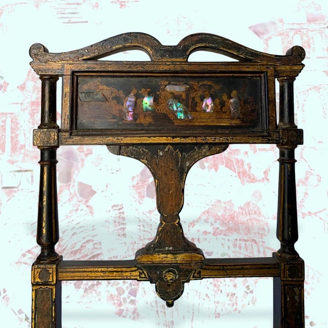 An antique wooden display case with intricate detailing, showcasing several pieces of iridescent pearl jewelry inside.