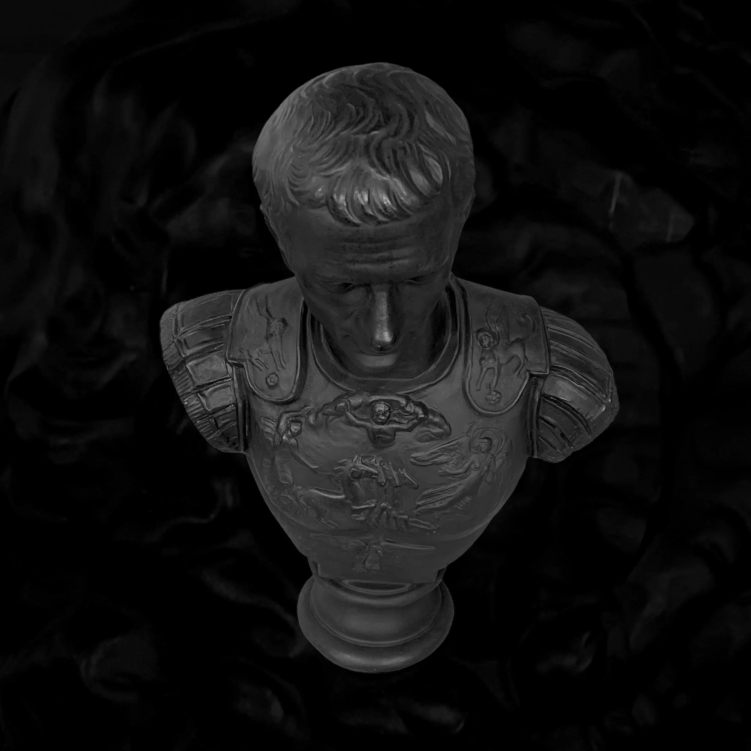 Black and white bust of a man wearing a decorated military uniform with detailed medals and symbols, viewed from above against a dark background.