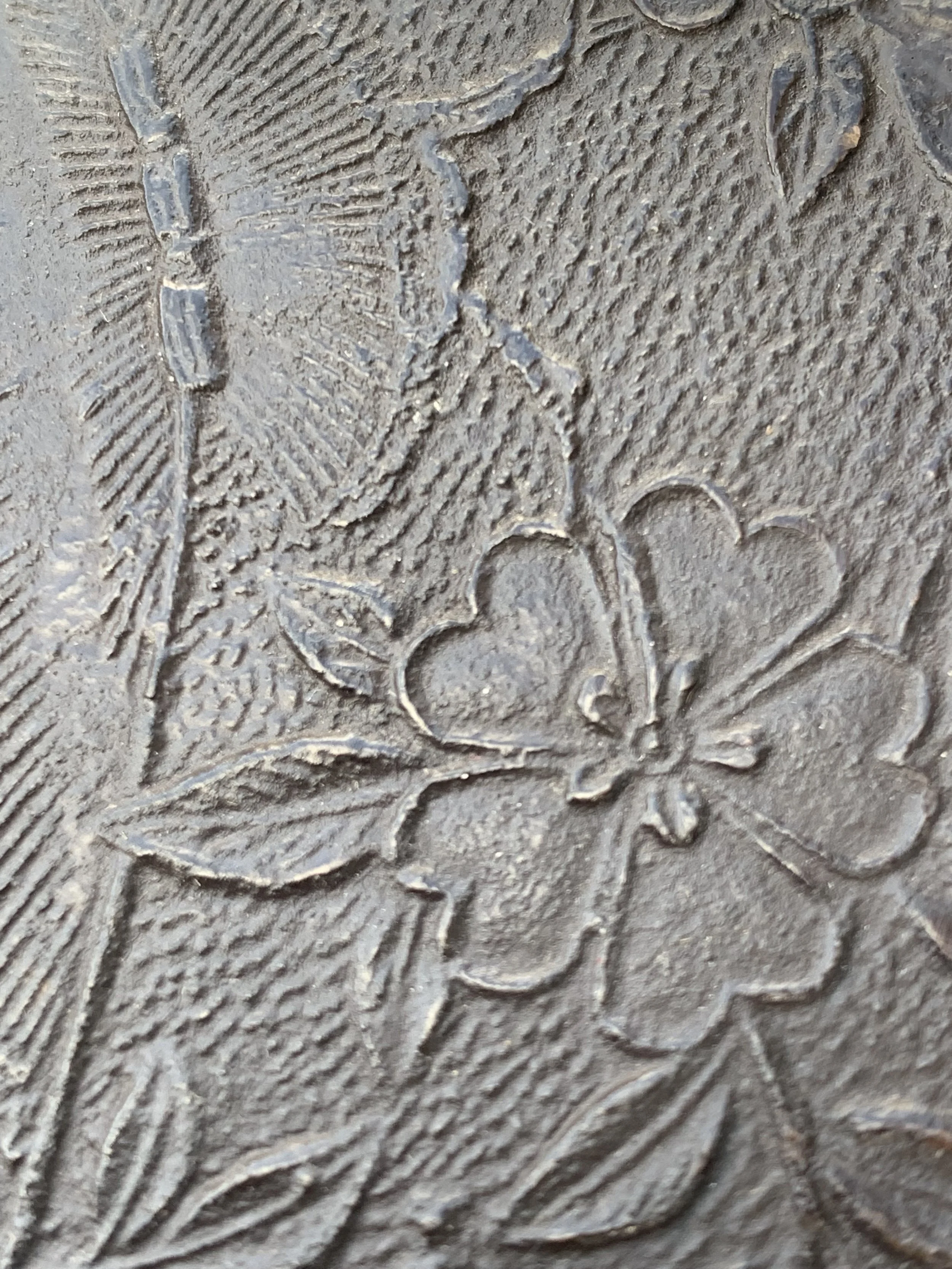 Close-up of an engraved flower design on a textured metallic surface.