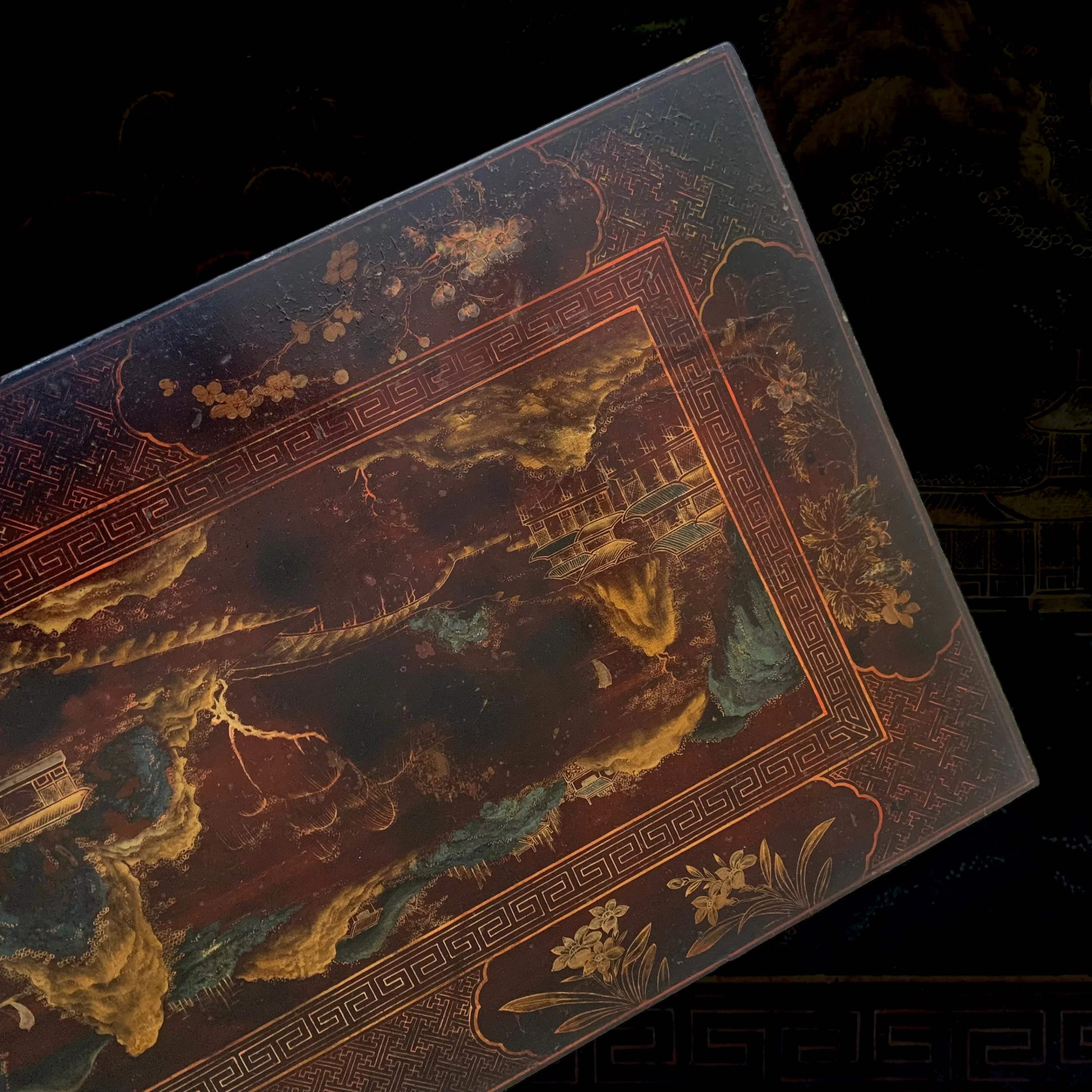 Close-up of a decorative book cover featuring traditional Chinese landscape art with mountains, water, trees, and buildings, highlighted by gold and red detailing.